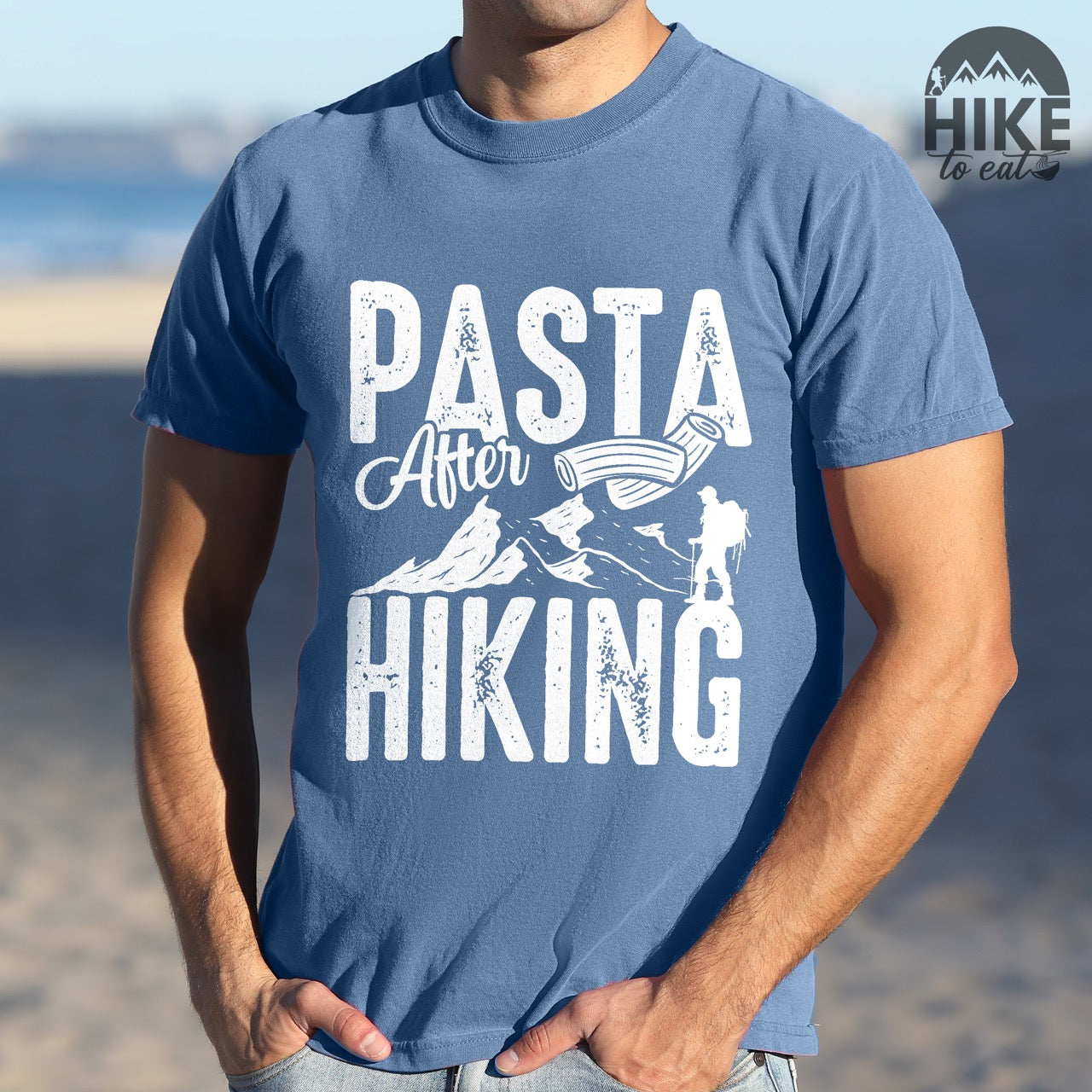 Man wearing Blue jean "Pasta after hiking" colored vintage tee with bold typography, birds, mountains, illustrated pieces of pasta, and backpackers for pasta lovers.