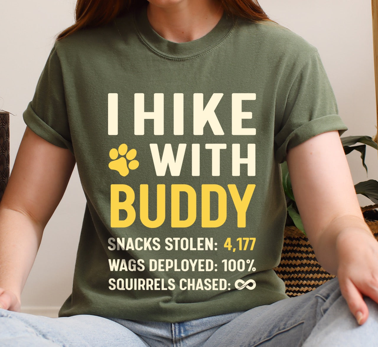 Woman wearing moss Personalized dog hiking shirt I Hike with custom pet name  of Buddy featuring paw print graphic, funny adventure statistics including snacks stolen of 4,177 wags deployed and squirrels chased on Comfort Colors tee for outdoor pet lovers