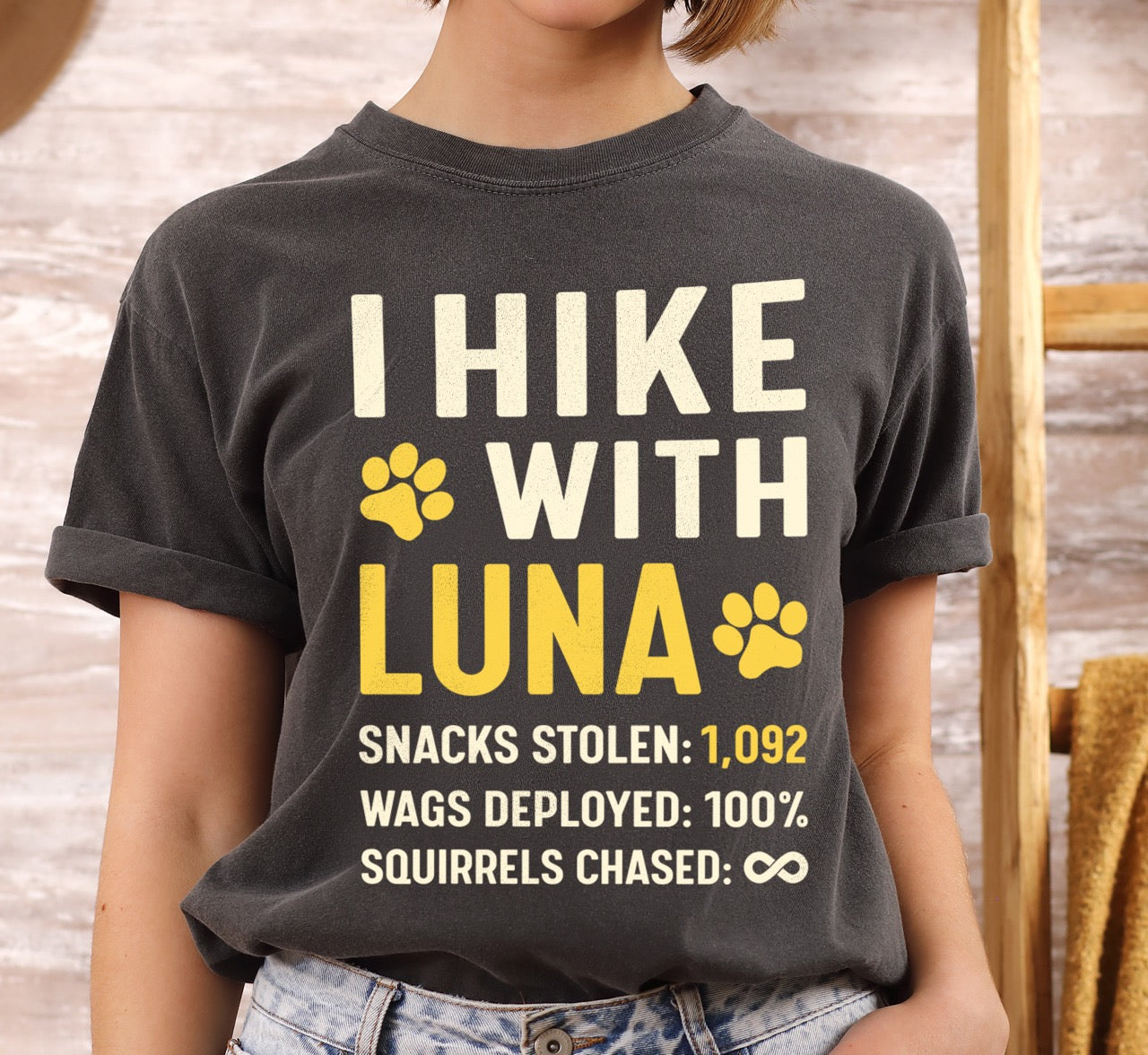 Woman wearing pepper (grey) Personalized dog hiking shirt I Hike with custom pet name of Luna  featuring paw print graphic, funny adventure statistics of 1,092  including snacks stolen wags deployed and squirrels chased on Comfort Colors tee for outdoor pet lovers