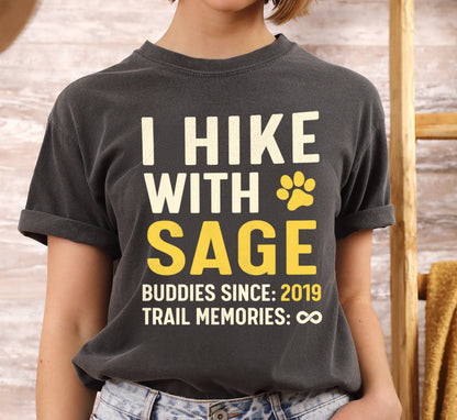 Pepper (Dark Gray) graphic t-shirt with 'Trail Buddies Personalized' design featuring 'I Hike with' text and customizable pet name field in cream and yellow lettering with paw prints, plus customizable year for 'buddies since' and trail memories infinity.