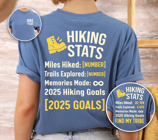 Blue Jean (Denim Blue) Hike to Eat t-shirt front and back view showing small chest detail and large back design featuring 'Hiking Stats Personalized' with yellow hiking boot icon, customizable miles hiked and trails explored numbers, memories made infinity, and customizable 2025 hiking goals, shown with close-up detail displaying example stats and 'Find My Tribe' goal.