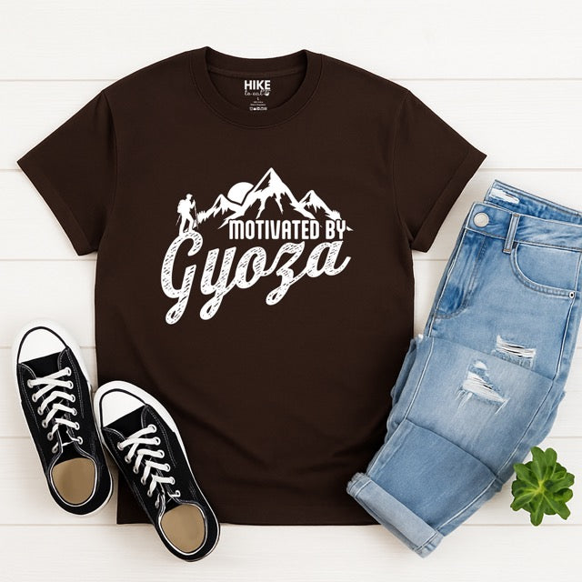 Dark Chocolate (brown) Motivated by Gyoza statement tee with distressed typography, mountain peaks, and hiker silhouette for gyoza lovers and japanese food lovers - flat layed with pants and shoes