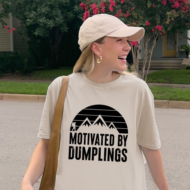 woman wearing sand (beige) colored Motivated by Dumplings retro statement tee with sunset design, mountain peaks, and hiker silhouette for dumpling lovers