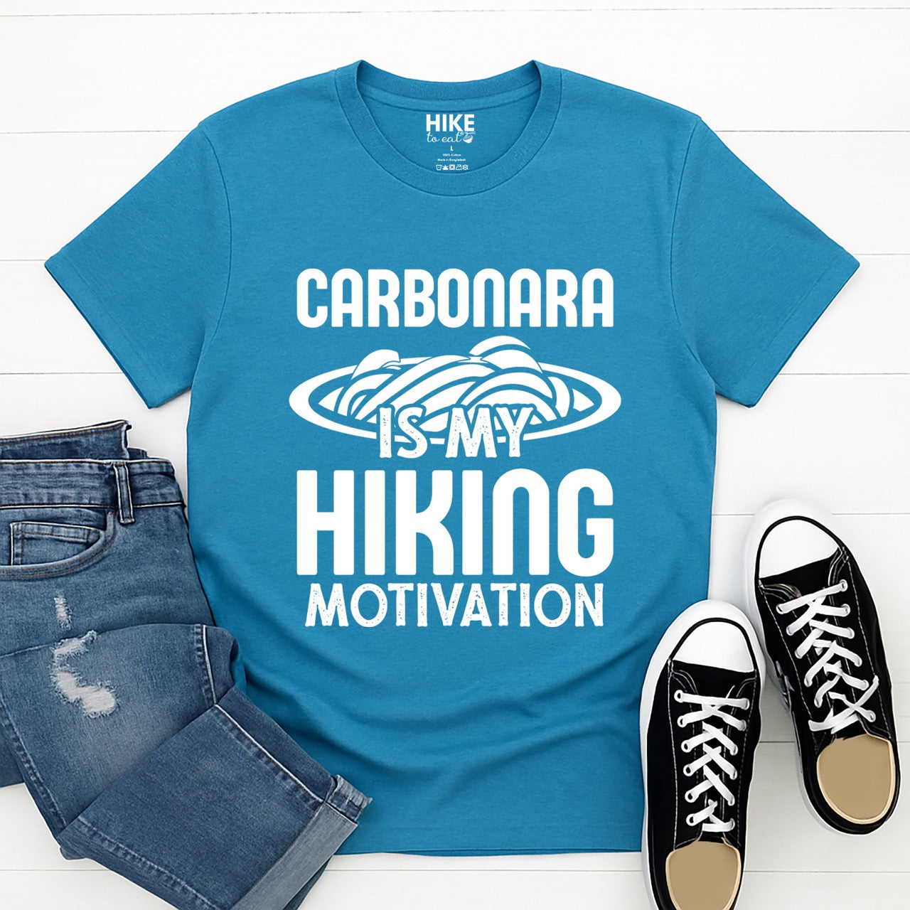 Saphire (blue)  Carbonara is my Hiking Motivation statement tee with bold typography and pasta bowl illustration for carbonara enthusiasts and hikers - layed flat with jeans and shoes