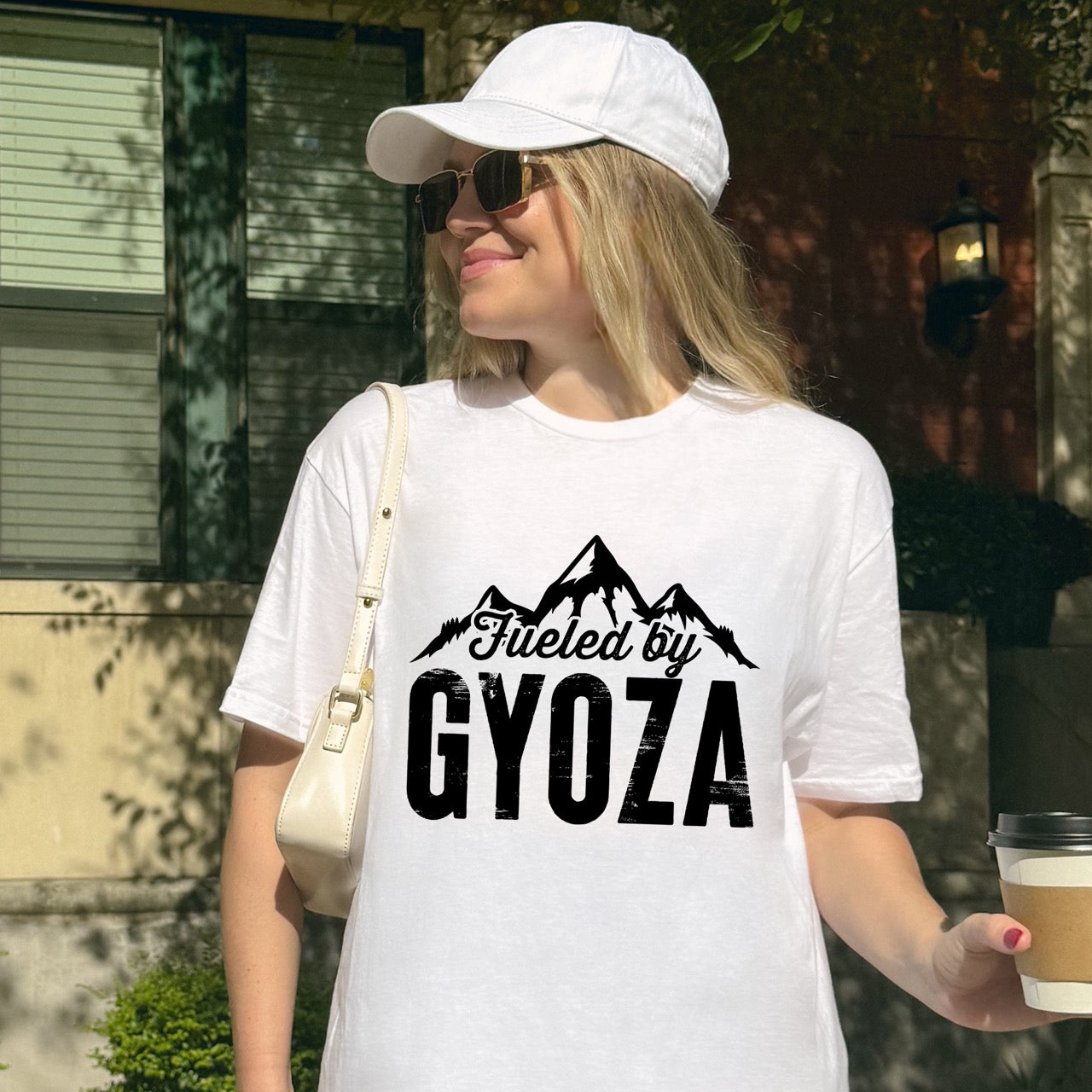 woman wearing white Fueled by Gyoza statement tee with distressed bold typography and mountain peaks for dumpling enthusiasts and hikers