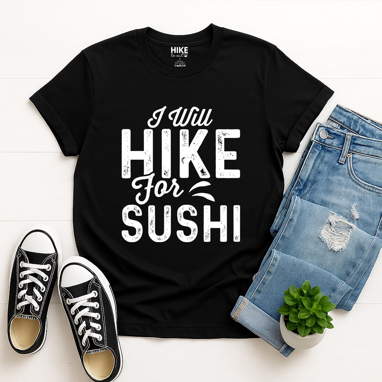 black I Will Hike for Sushi statement tee with distressed bold typography and elegant script lettering for Japanese food-loving outdoor enthusiasts and hikers with jeans and shoes