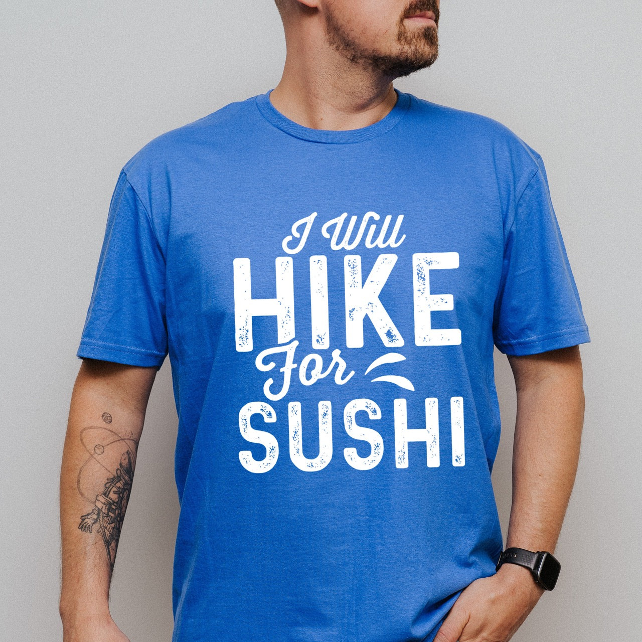 man wearing royal blue I Will Hike for Sushi statement tee with distressed bold typography and elegant script lettering for Japanese food-loving outdoor enthusiasts and hikers