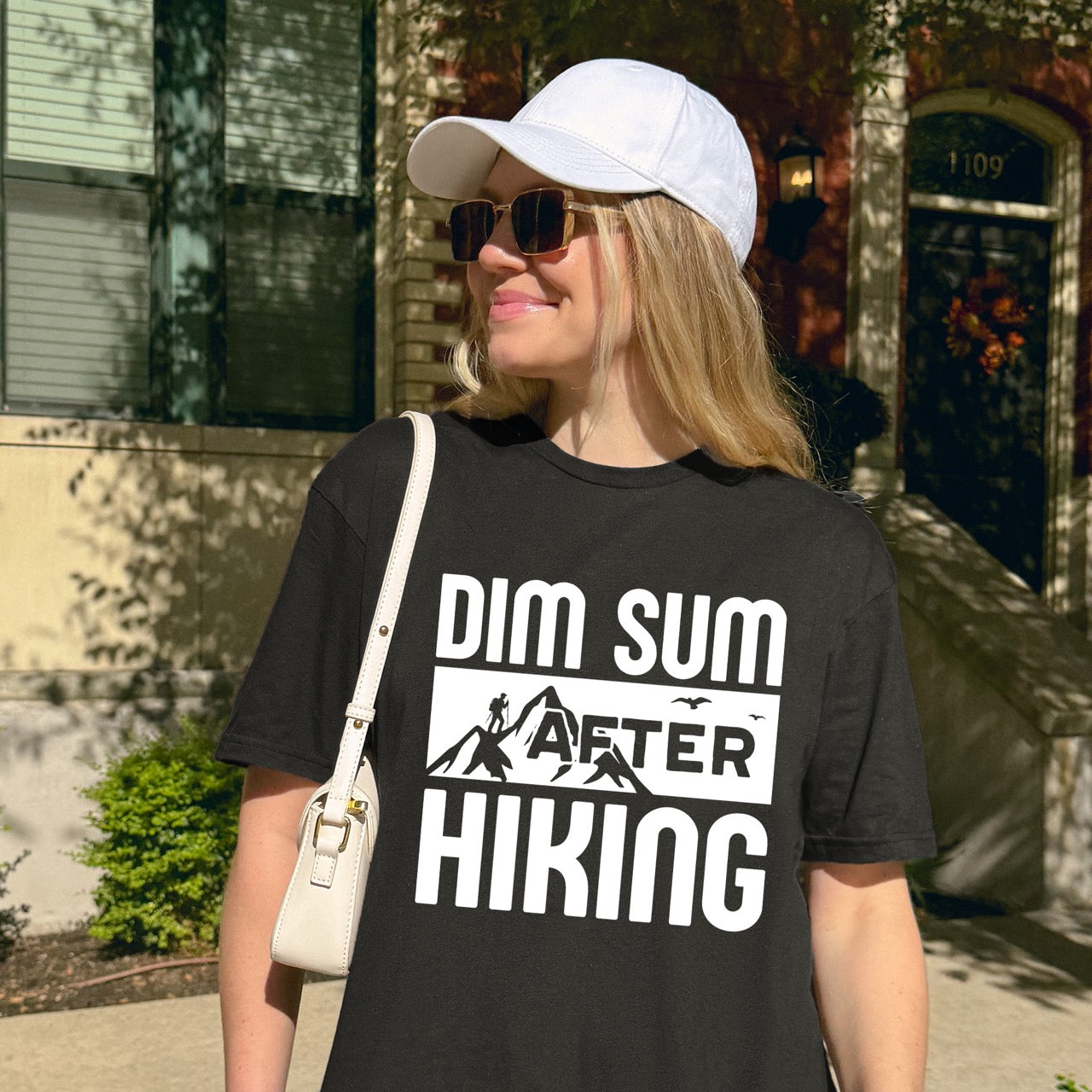 woman wearing BLACK Dim Sum after Hiking statement tee with bold typography, mountain peaks, hiker silhouette, and flying birds for Chinese food-loving outdoor enthusiasts, hikers and foodies