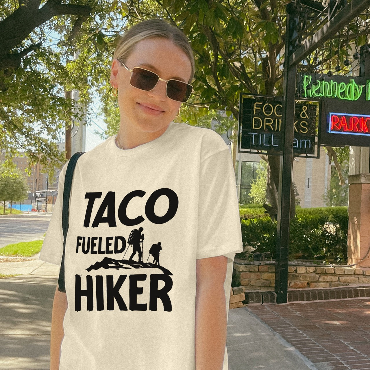 Woman wearing Natural (beige) Royal blue Taco Fueled Hiker statement tee with bold distressed typography and two hiker silhouettes on mountain ridge for Mexican food-loving outdoor enthusiasts, hikers and foodies