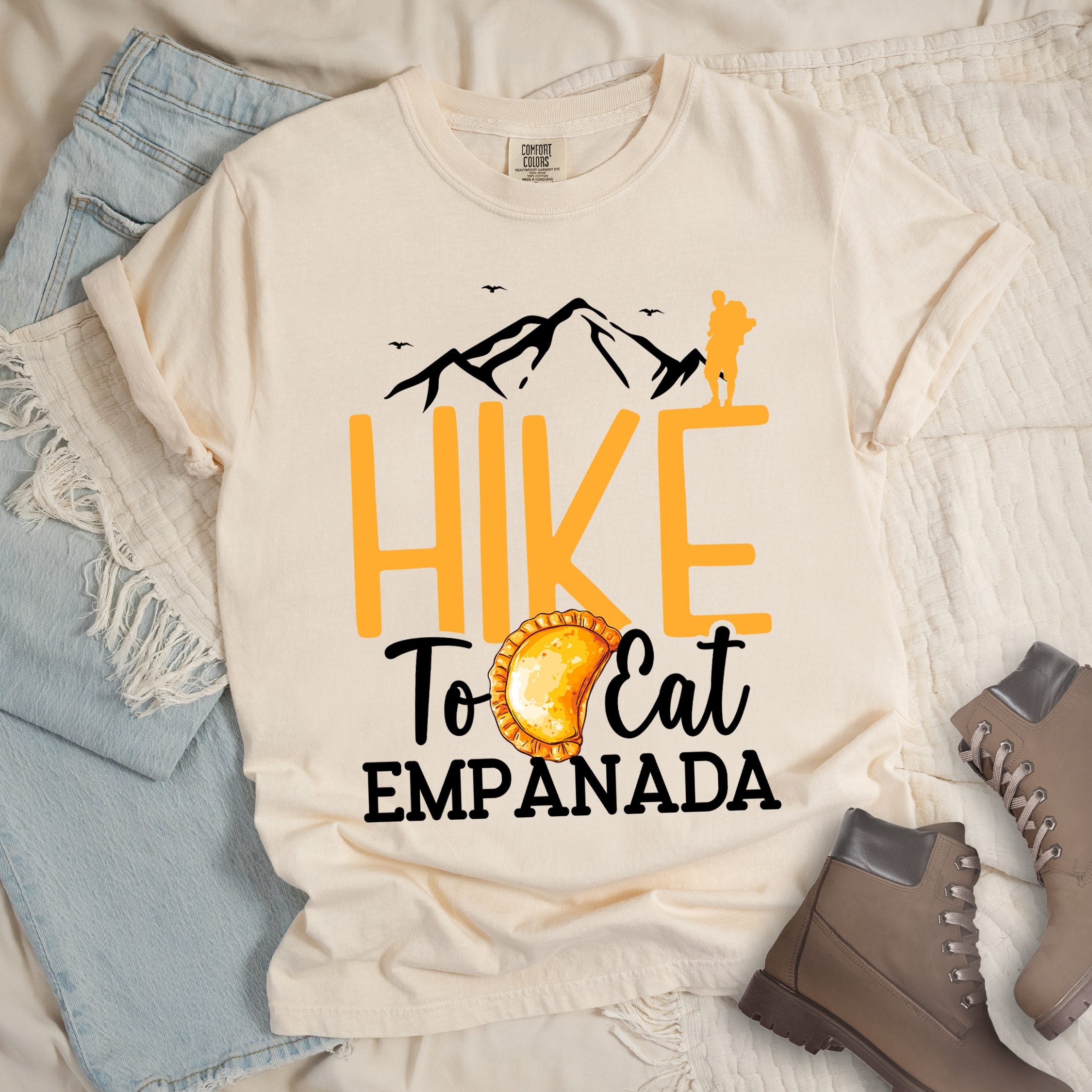 Ivory shirt with Hiking Design featuring the phrase “Hike to Eat Empanada” and a hiker silhouette above a plate of empanada.