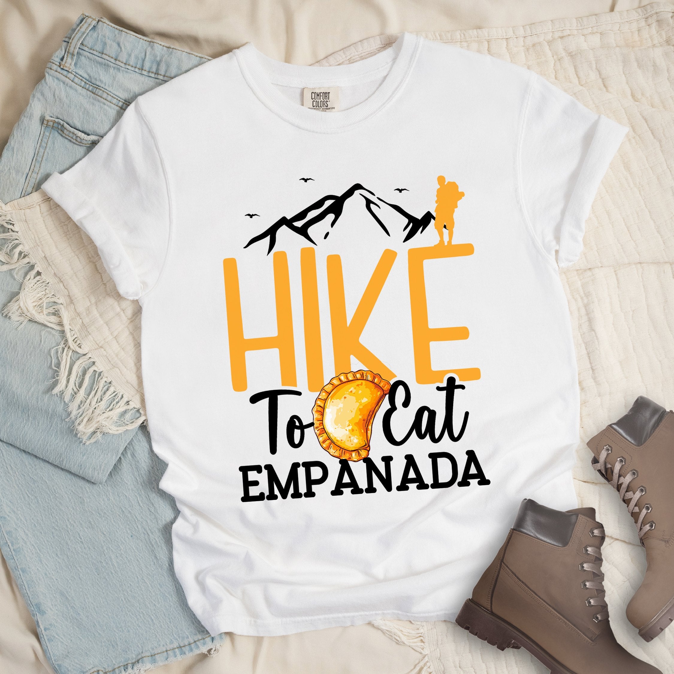 White shirt with Hiking Design featuring the phrase “Hike to Eat Empanada” and a hiker silhouette above a plate of empanada.