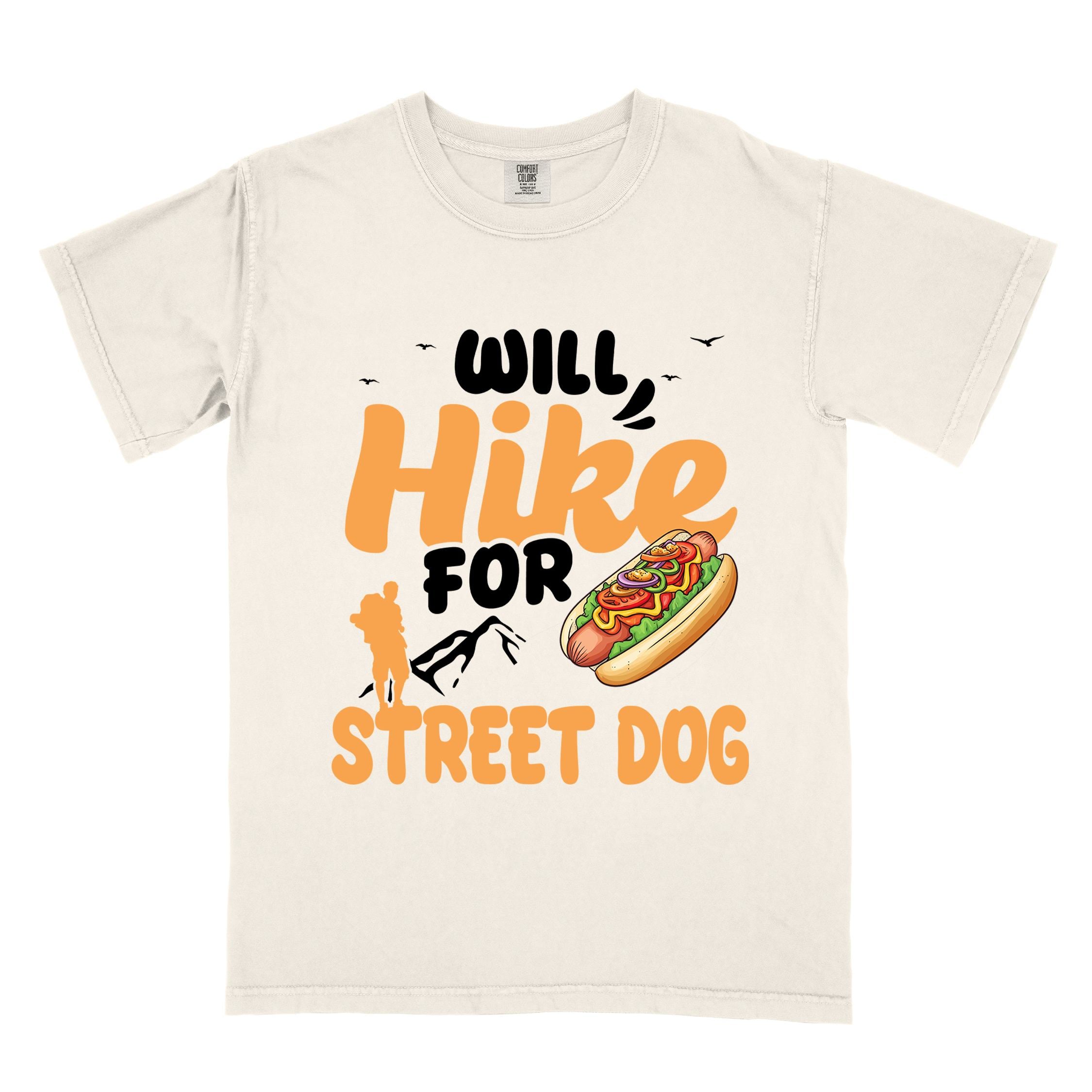 Ivory "Will hike for street dog" colored vintage tee with bold typography, illustrated freshly bratwurst in a bun, mountains, birds, and backpackers for street dog lovers.