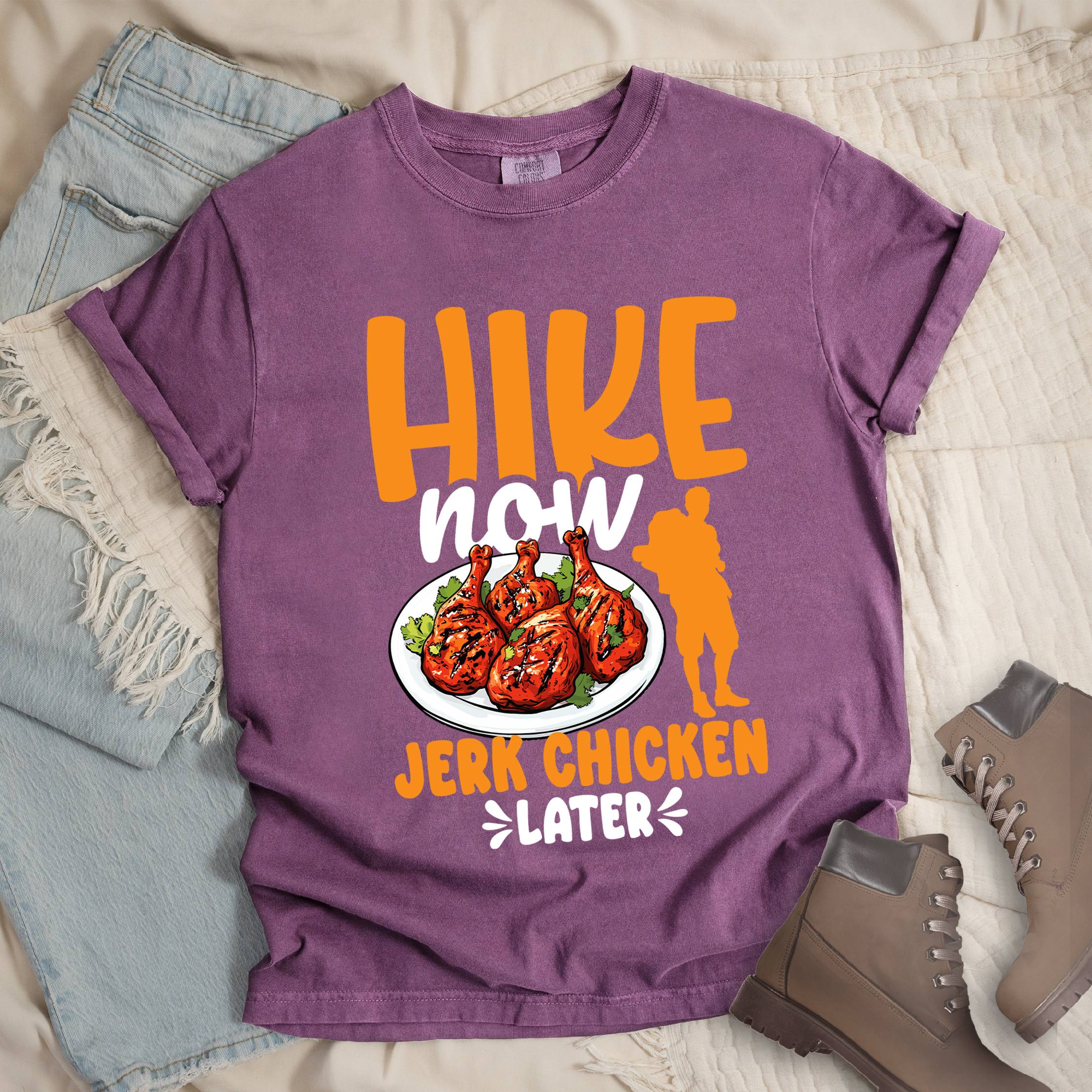 Dark pink shirt with Hiking Design featuring the phrase “Hike Now Jerk Chicken Later” and an illustration of jerk chicken drumsticks.