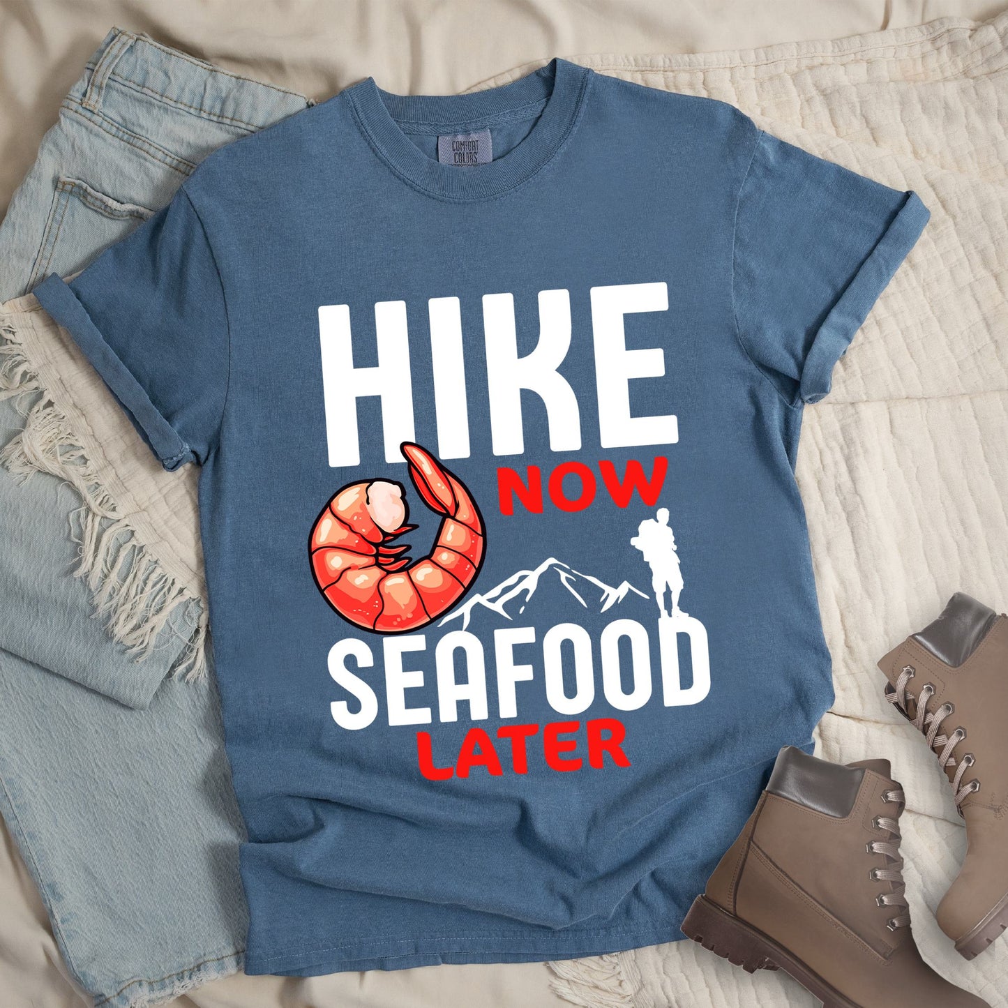 Dark blue shirt with Hiking Design featuring the phrase “Hike Now Seafood Later” and an illustration of a shrimp with a mountain outline.