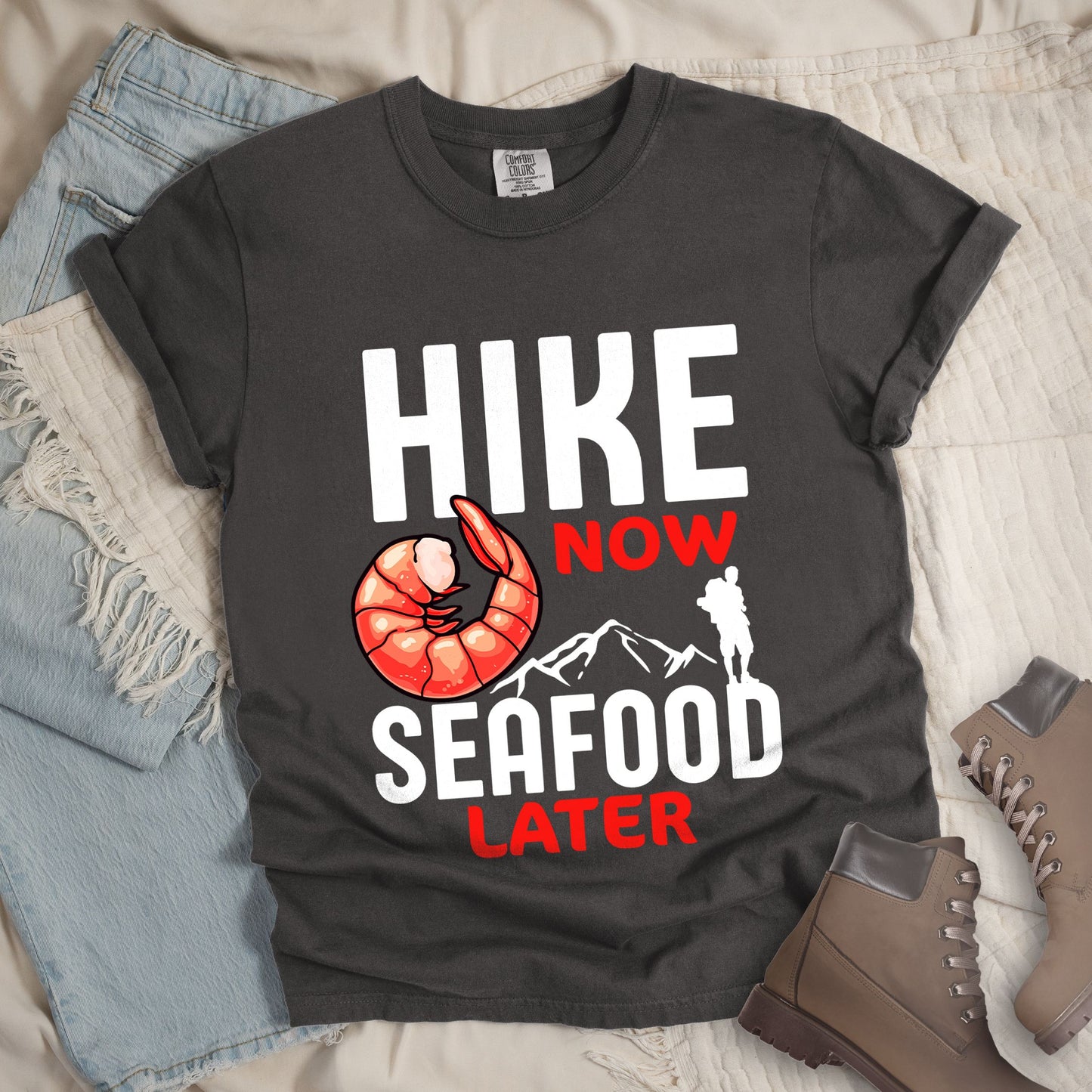 Dark grey shirt with Hiking Design featuring the phrase “Hike Now Seafood Later” and an illustration of a shrimp with a mountain outline.