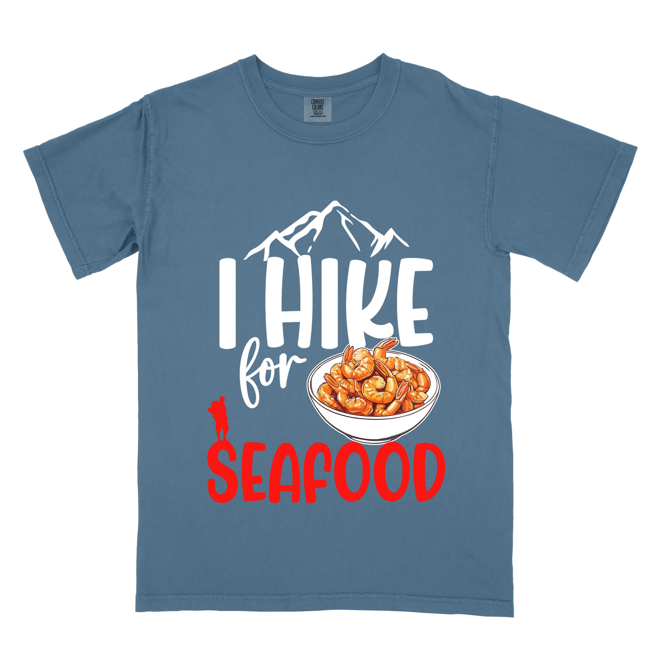 blue jean "I hike for seafood" colored vintage tee with bold typography, illustrated shrimps on a bowl, mountains, birds, and backpackers for seafood  lovers.