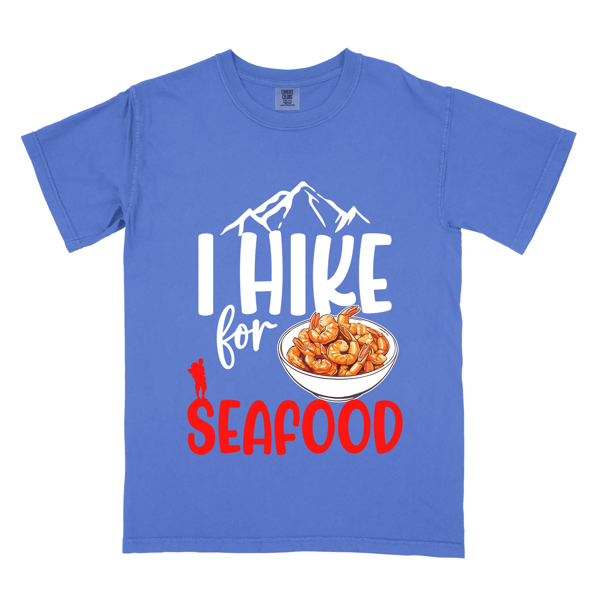 flo blue "I hike for seafood" colored vintage tee with bold typography, illustrated shrimps on a bowl, mountains, birds, and backpackers for seafood  lovers.