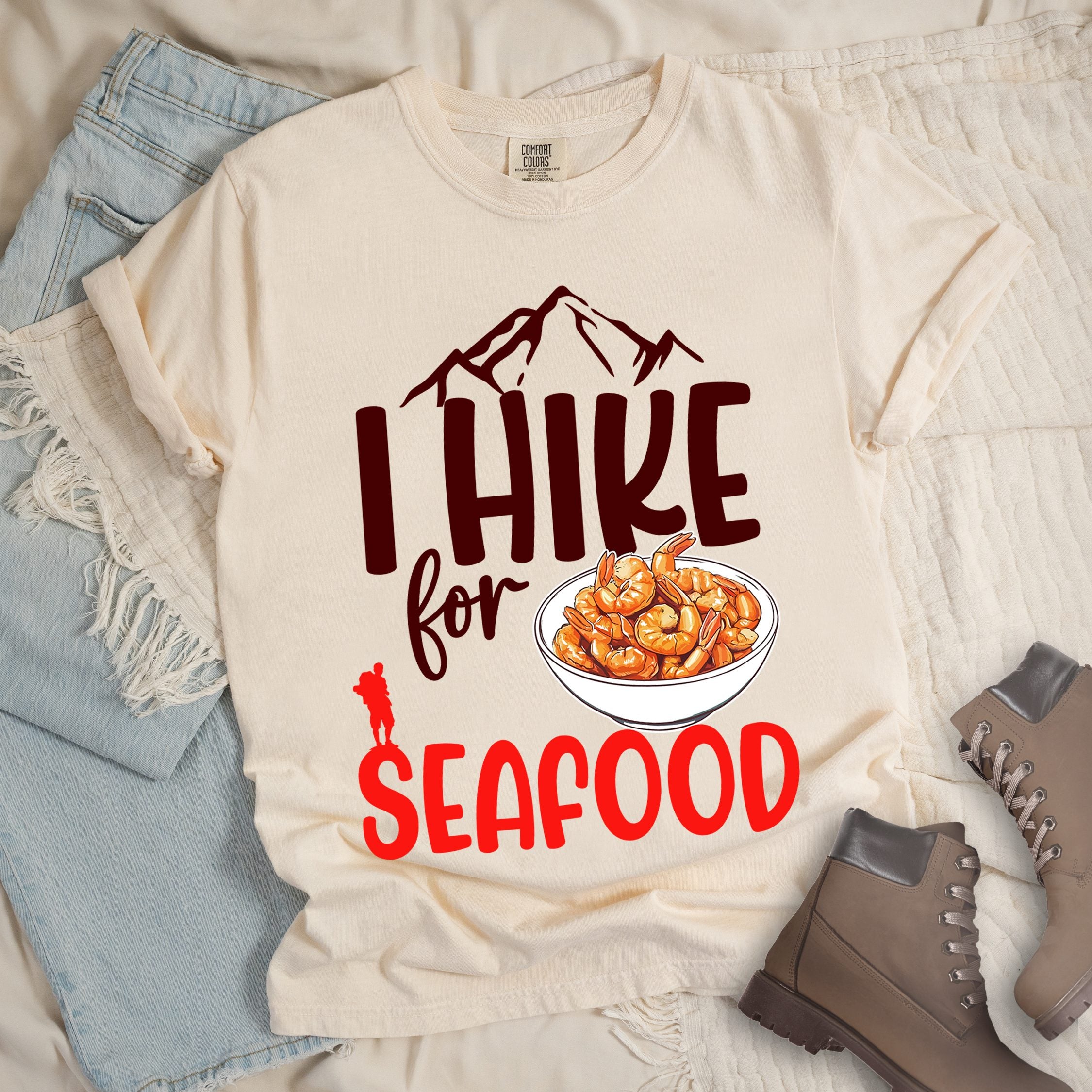 Ivory shirt with Hiking Design featuring the phrase “I Hike for Seafood” and an illustration of a bowl of shrimp with a hiker silhouette.