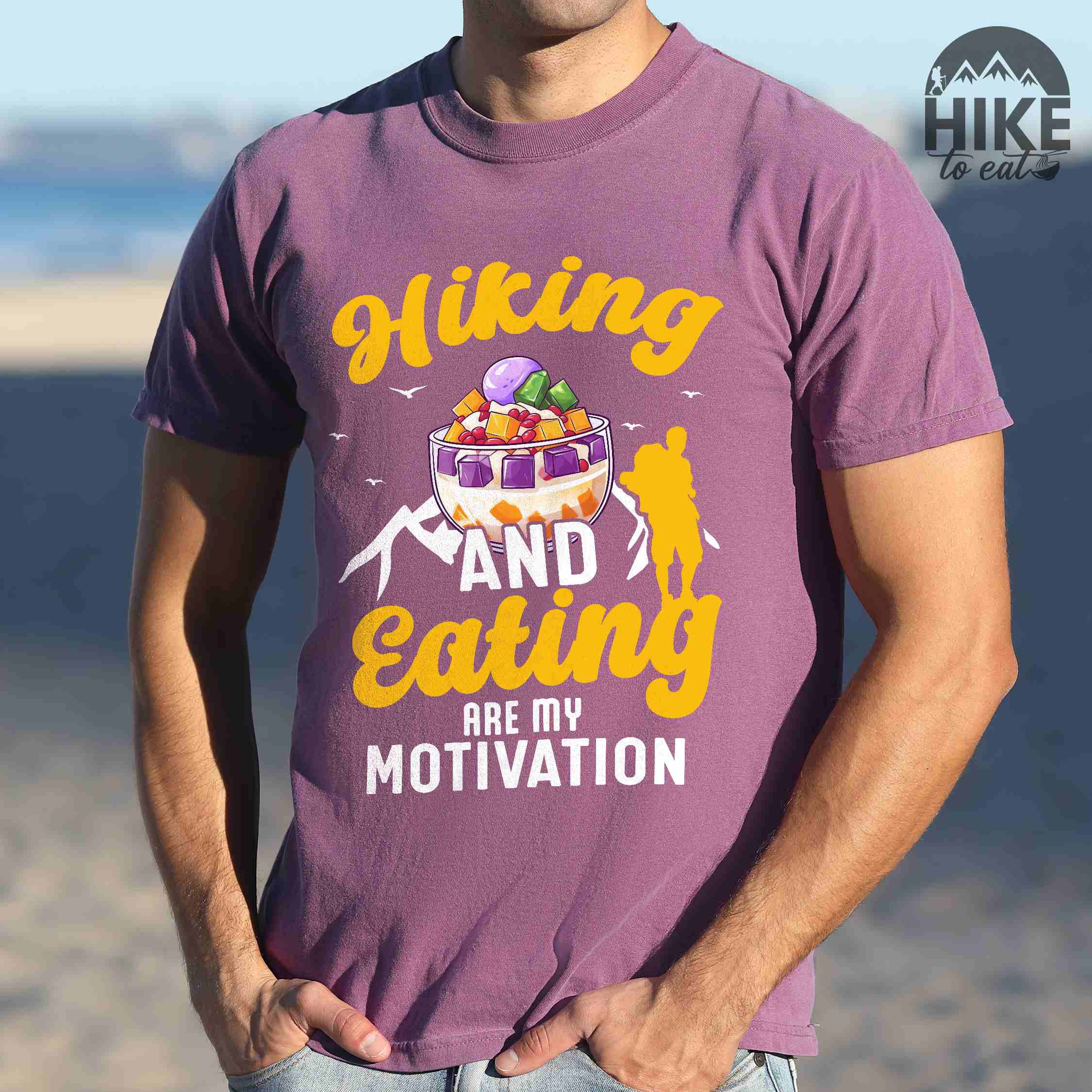 Man wearing berry "hiking and eating are my motivation" colored vintage tee with bold typography, illustrated halo-halo dessert, and backpackers for filipino dessert lovers.