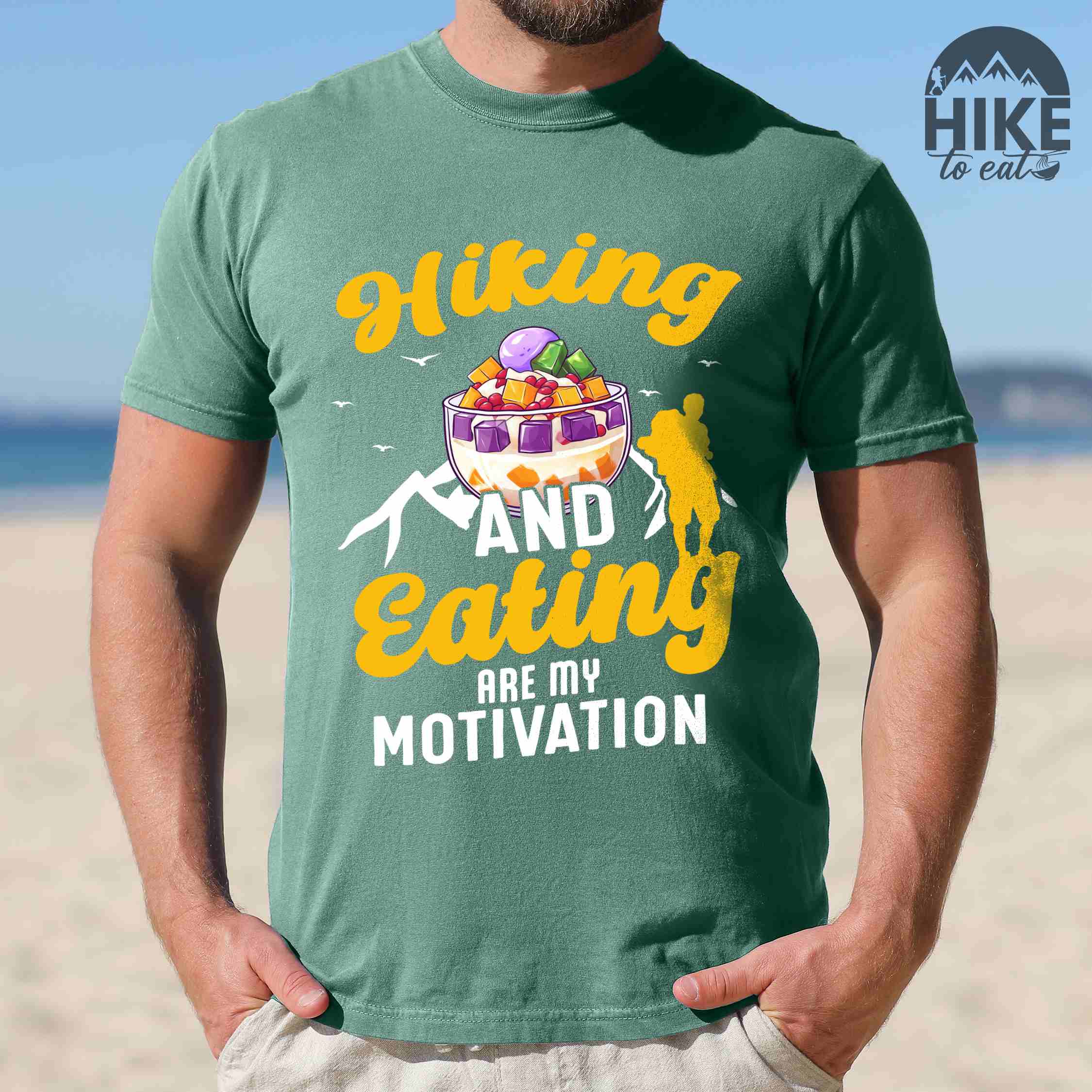 Man wearing light green "hiking and eating are my motivation" colored vintage tee with bold typography, illustrated halo-halo dessert, and backpackers for filipino dessert lovers.
