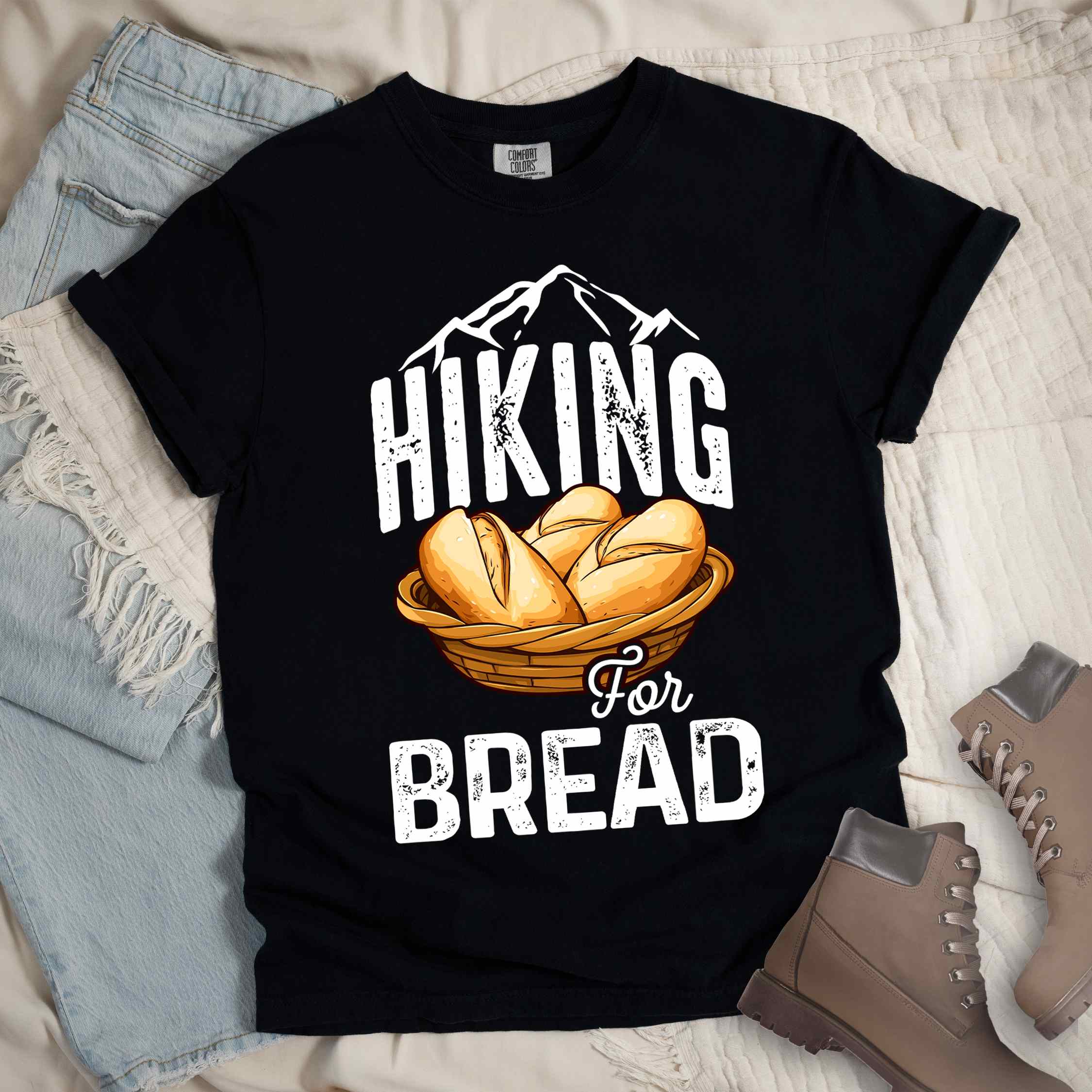 Black "Hiking for bread" colored statement tee with flowing script typography, bold lettering, and freshly baked bread illustration for pastry-loving outdoor enthusiasts, hikers and foodies