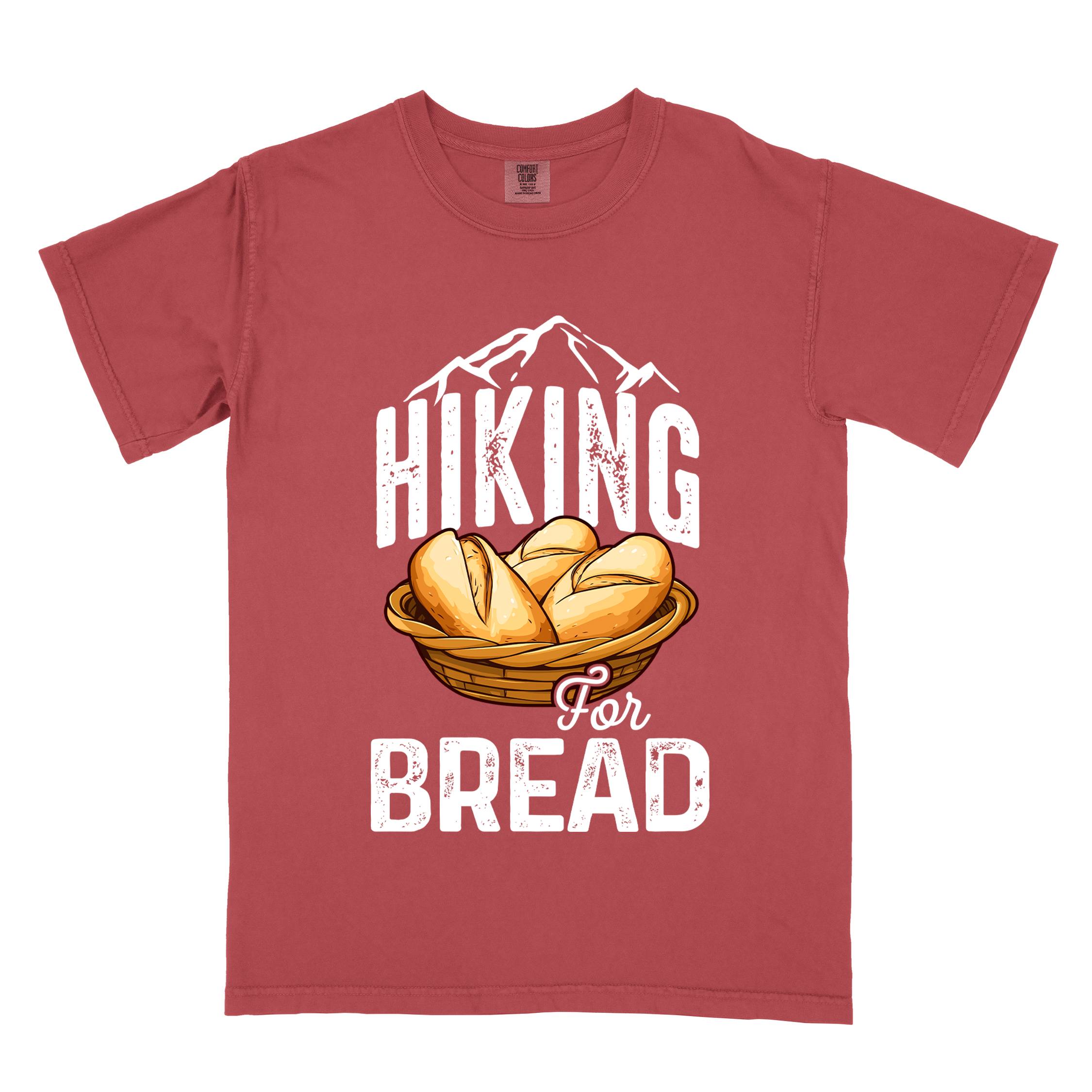 Crimson "Hiking for bread" colored statement tee with flowing script typography, bold lettering, and freshly baked bread illustration for pastry-loving outdoor enthusiasts, hikers and foodies