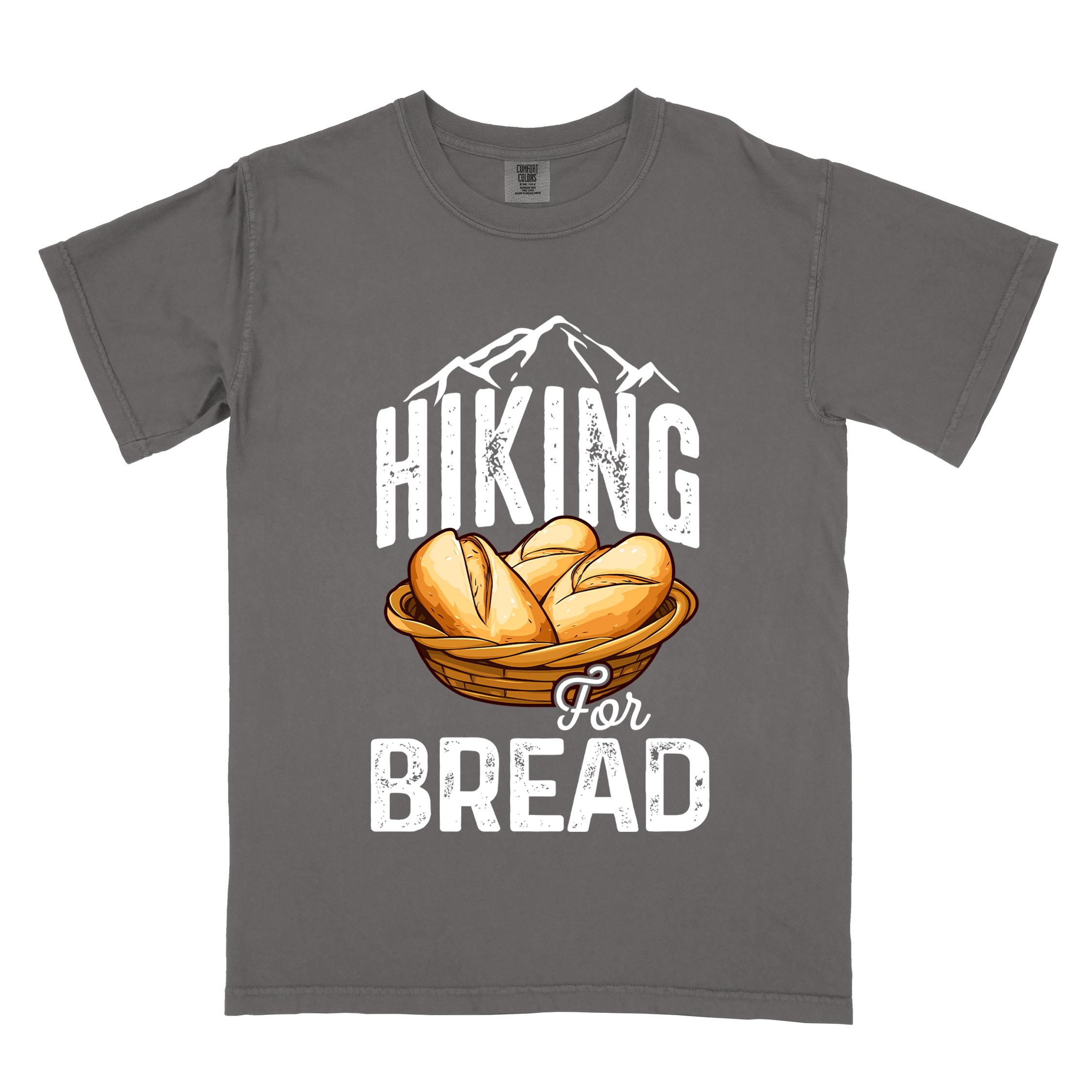Pepper "Hiking for bread" colored statement tee with flowing script typography, bold lettering, and freshly baked bread illustration for pastry-loving outdoor enthusiasts, hikers and foodies