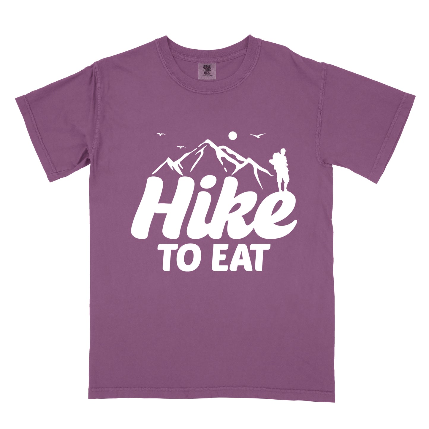 Berry (Dark Violet) t-shirt with white text reading "Hike TO EAT". "Hike" appears in large white script letters with white mountain outlines above it, and "TO EAT" in bold white text below it. Features a white silhouette of a hiker to the right of the mountains, white flying birds, and a white circle representing the sun. 