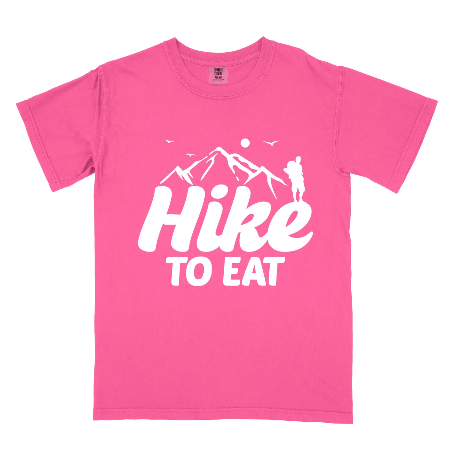 Crunchberry (Bright Pink) t-shirt with white text reading "Hike TO EAT". "Hike" appears in large white script letters with white mountain outlines above it, and "TO EAT" in bold white text below it. Features a white silhouette of a hiker to the right of the mountains, white flying birds, and a white circle representing the sun. 