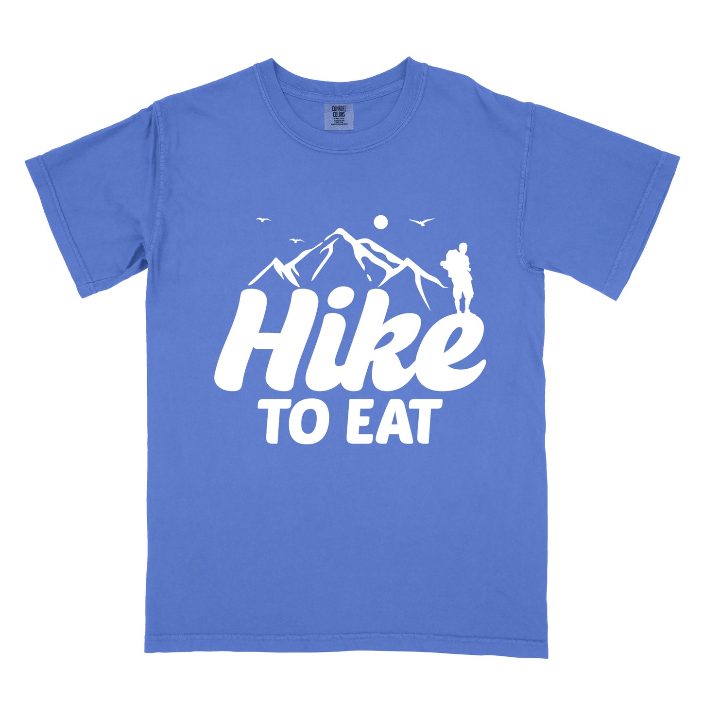 Flo Blue (Bright Blue) t-shirt with white text reading "Hike TO EAT". "Hike" appears in large white script letters with white mountain outlines above it, and "TO EAT" in bold white text below it. Features a white silhouette of a hiker to the right of the mountains, white flying birds, and a white circle representing the sun. 