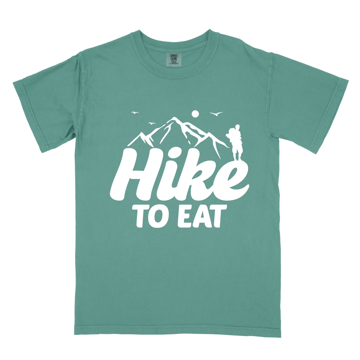 Light Green t-shirt with white text reading "Hike TO EAT". "Hike" appears in large white script letters with white mountain outlines above it, and "TO EAT" in bold white text below it. Features a white silhouette of a hiker to the right of the mountains, white flying birds, and a white circle representing the sun. 