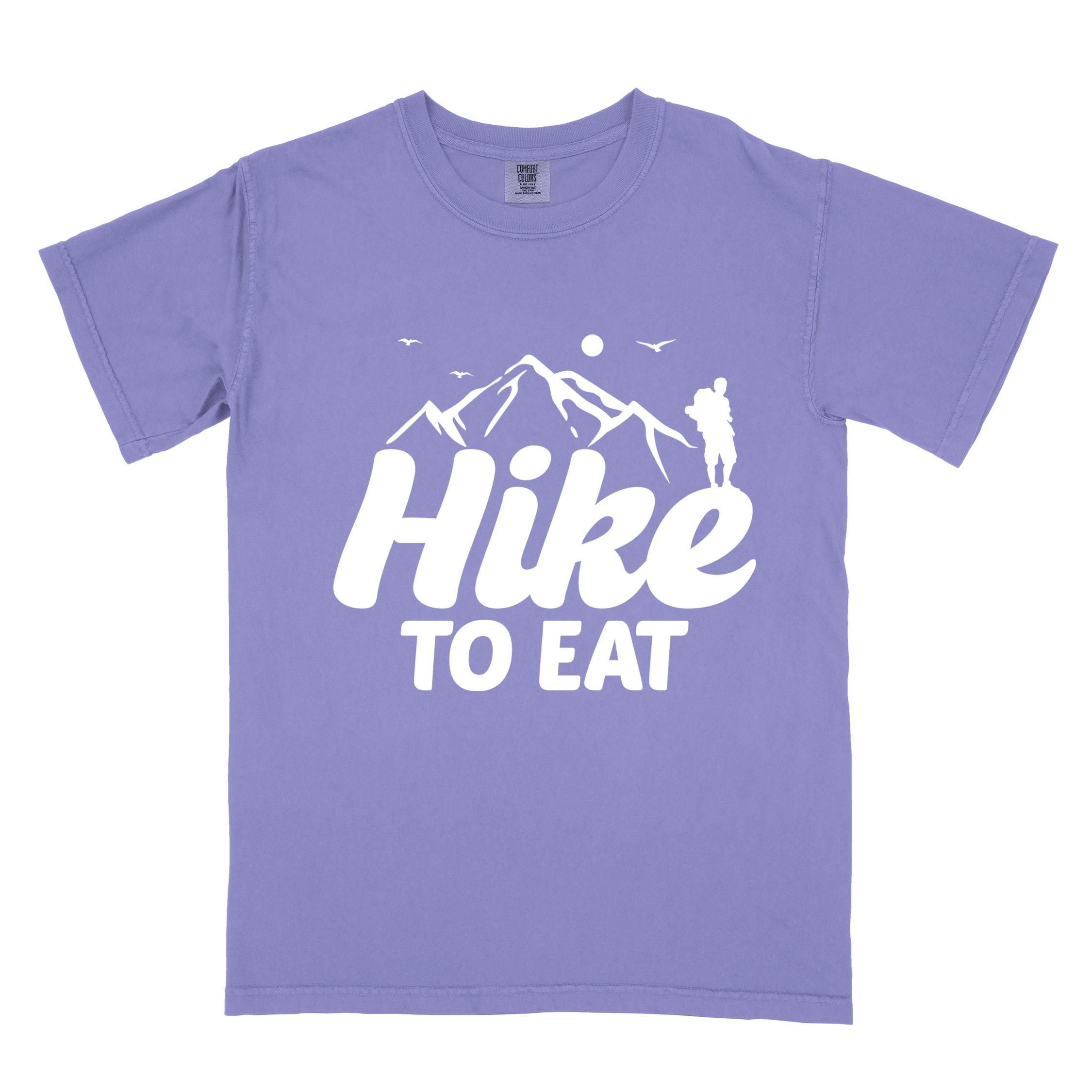 violet "Hike to Eat" colored statement tee with bold typography, mountains, birds, sunrise, perfect for food motivated individuals.