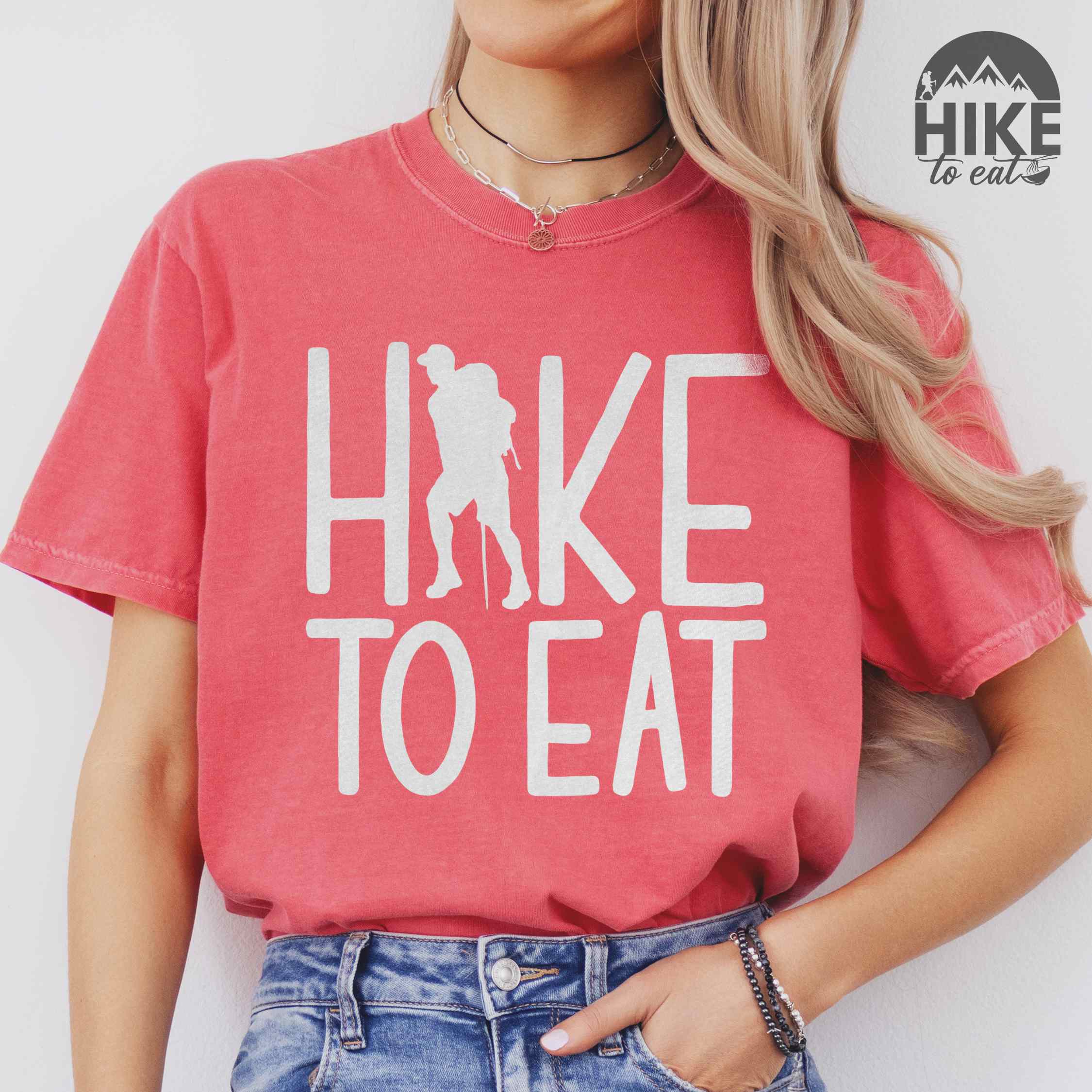 Woman wearing watermelon "Hike to Eat" colored statement tee with bold typography, perfect for food motivated individuals.