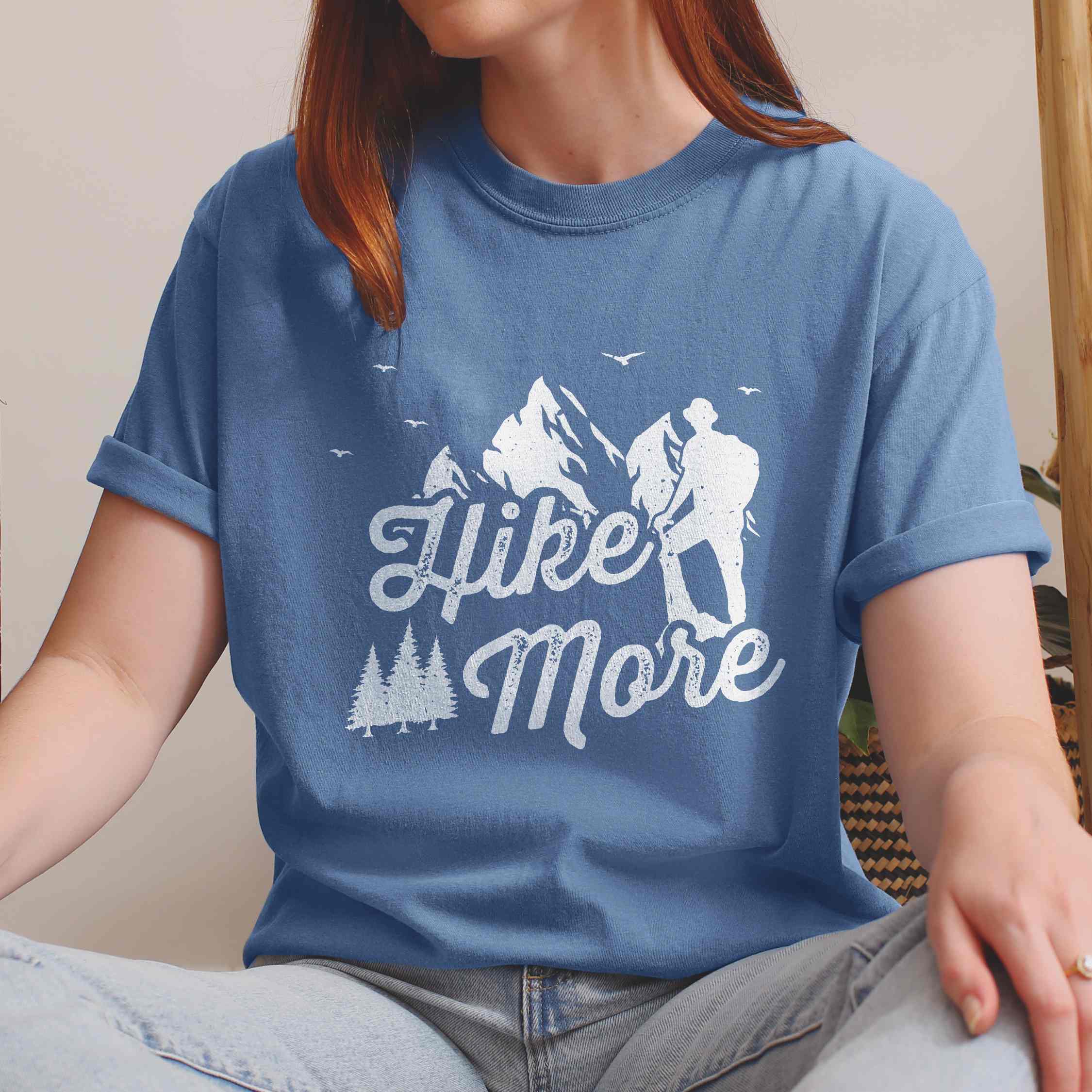 woman wearing blue jean "Hike More" colored statement tee with bold typography, mountains, birds, perfect for food motivated individuals.