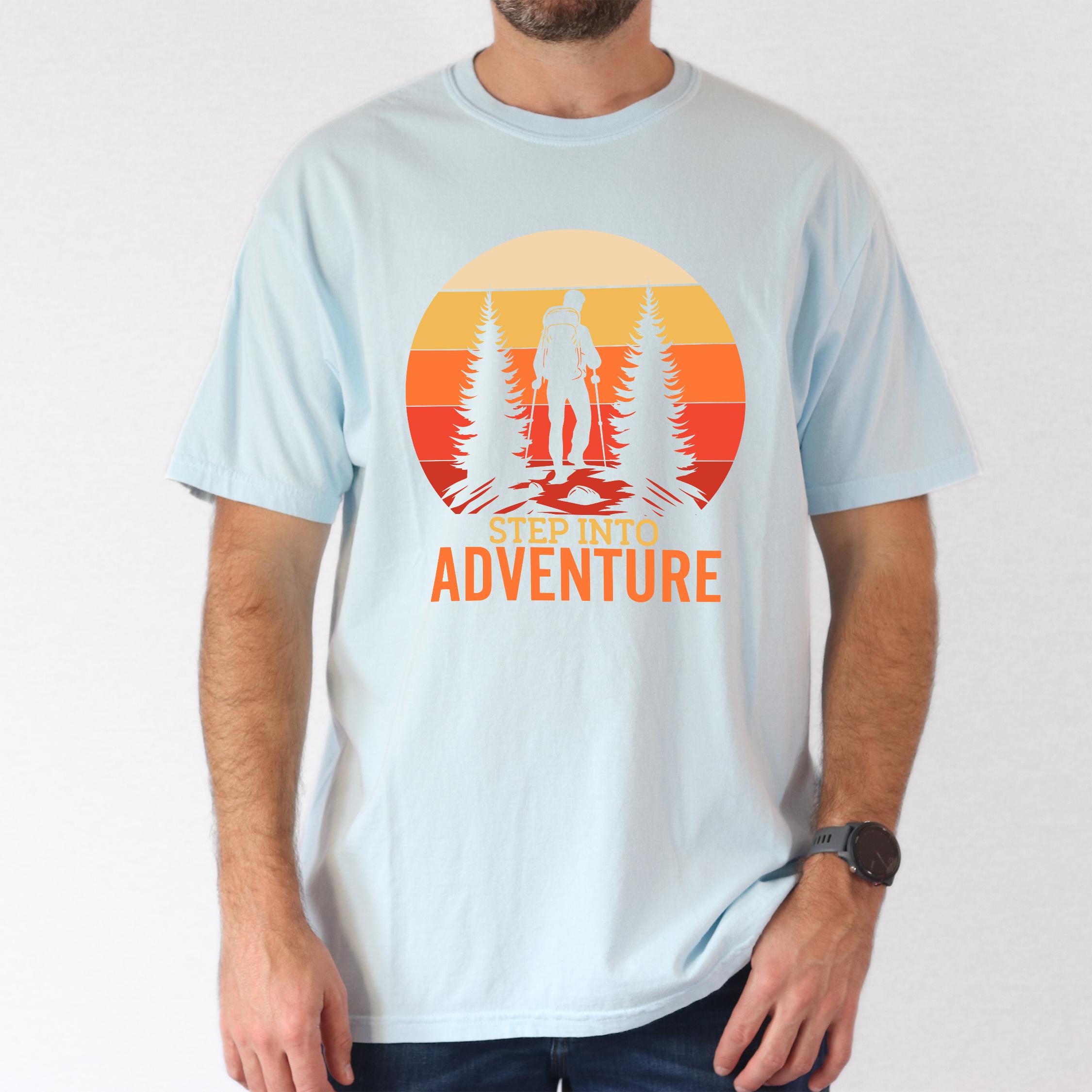 Man wearing chambray "Step into adventure" colored statement tee with bold typography, mountain, sunrise, perfect for adventure motivated individuals.