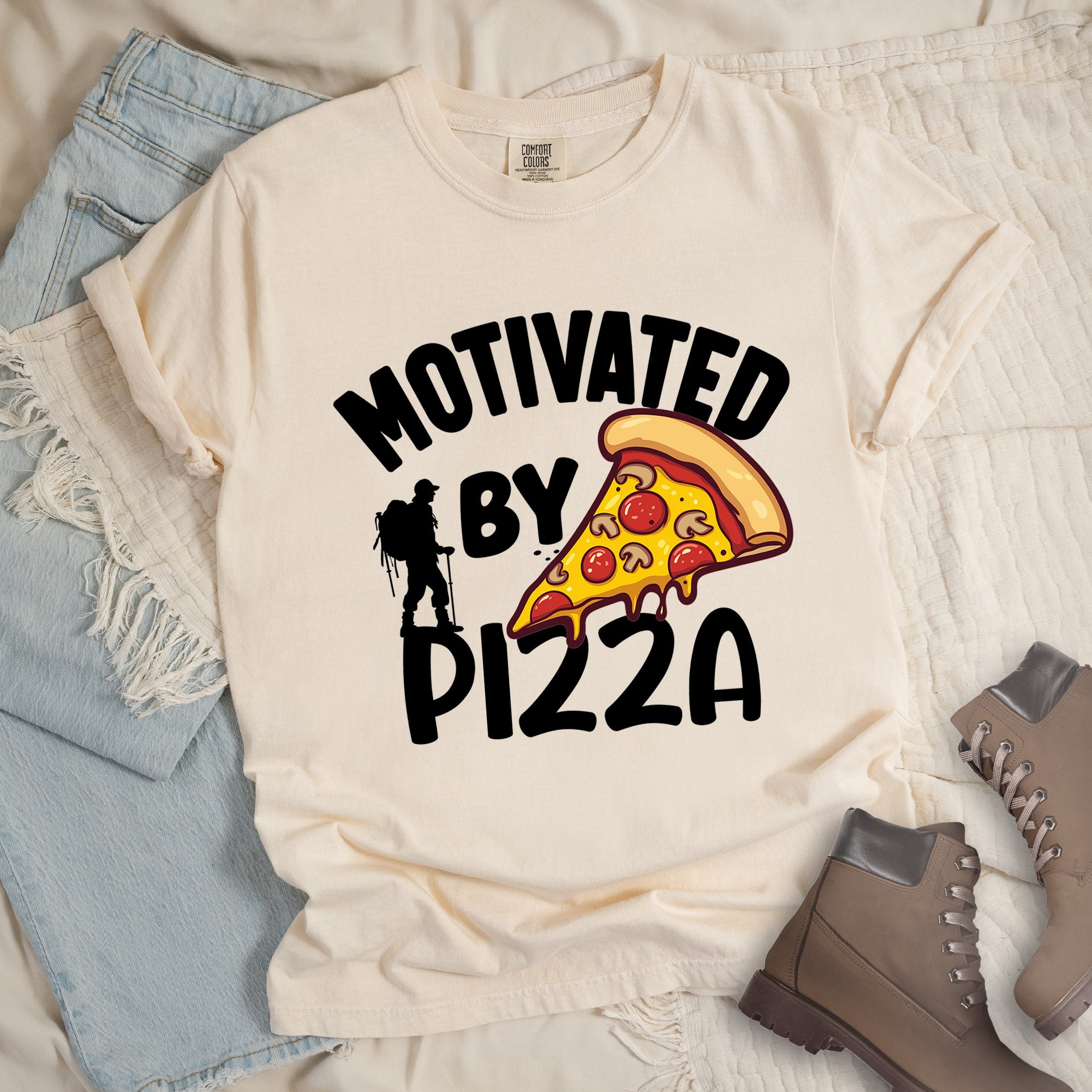 Ivory shirt showing a hiking design with 'Motivated By Pizza' phrase and an illustration of a slice of pizza