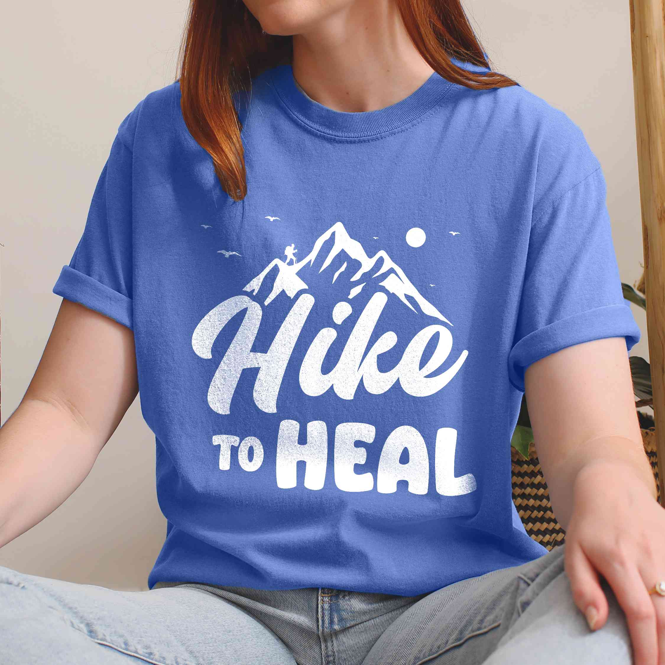 Woman wearing flo blue "Hike to Heal" colored statement tee with bold typography, mountain, sunrise, perfect for adventure driven individuals.
