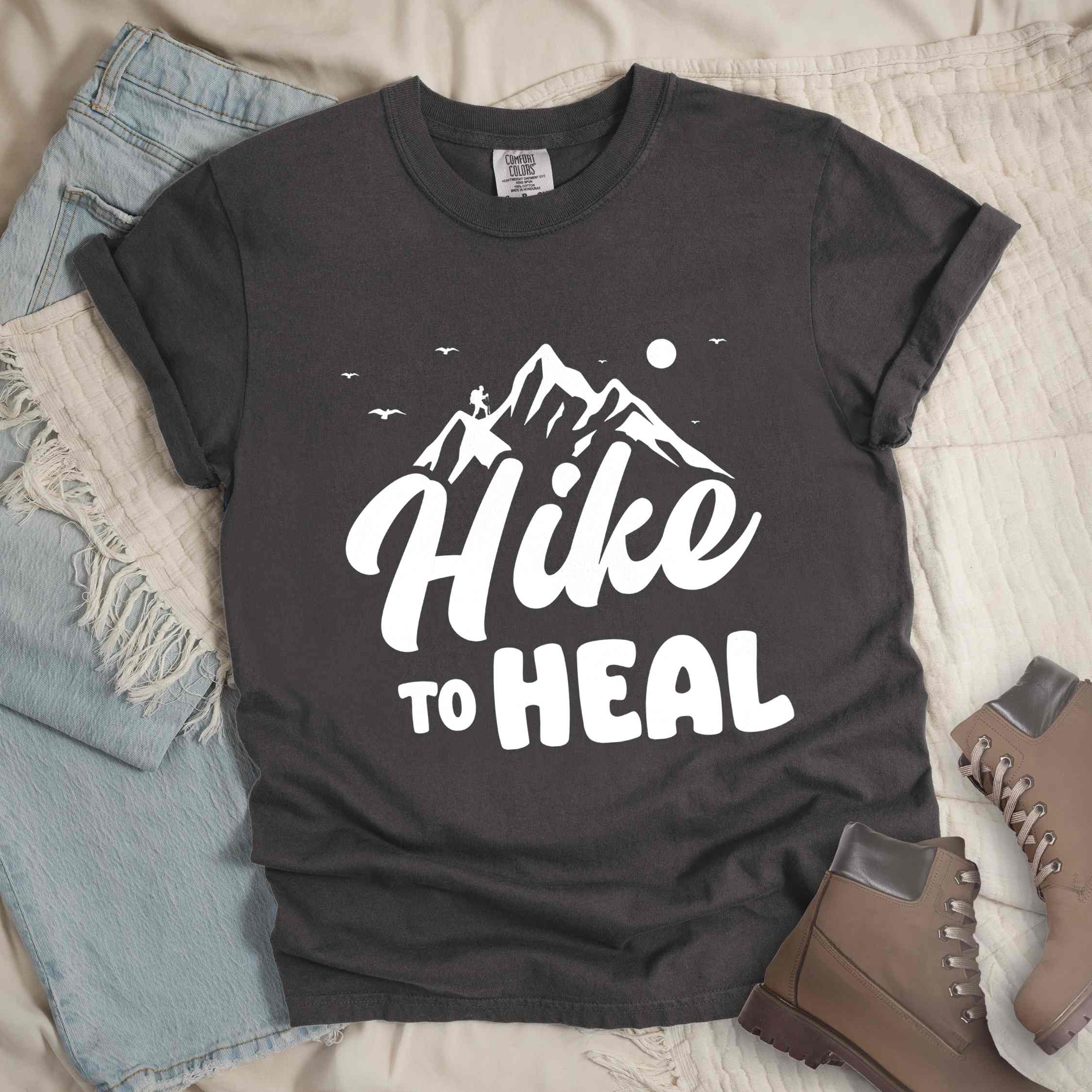 Pepper "Hike to Heal" colored statement tee with bold typography, mountain, sunrise, perfect for adventure driven individuals.