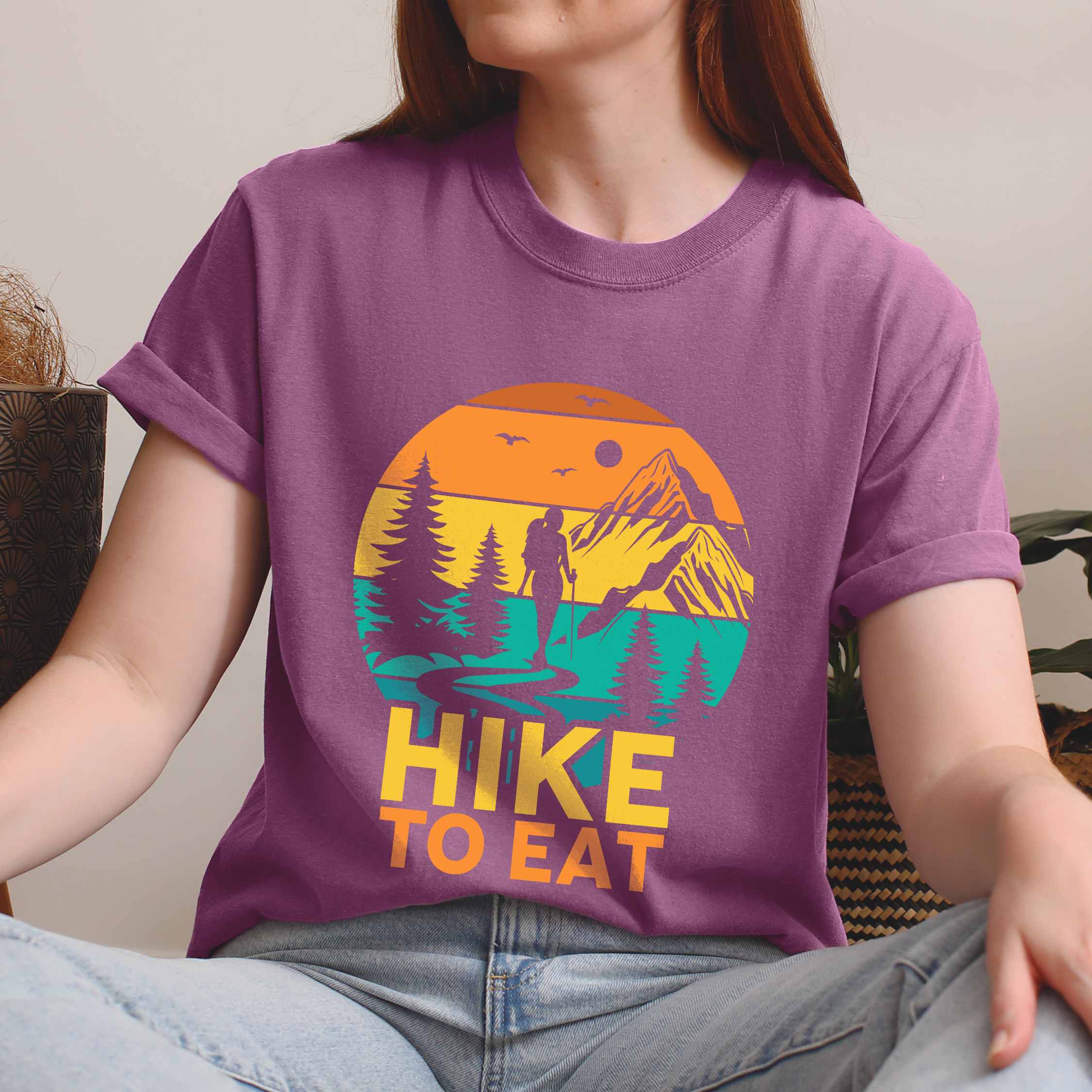 woman wearing berry "Hike to Eat" colored statement tee with bold typography, mountain, sunrise, perfect for adventure driven individuals.