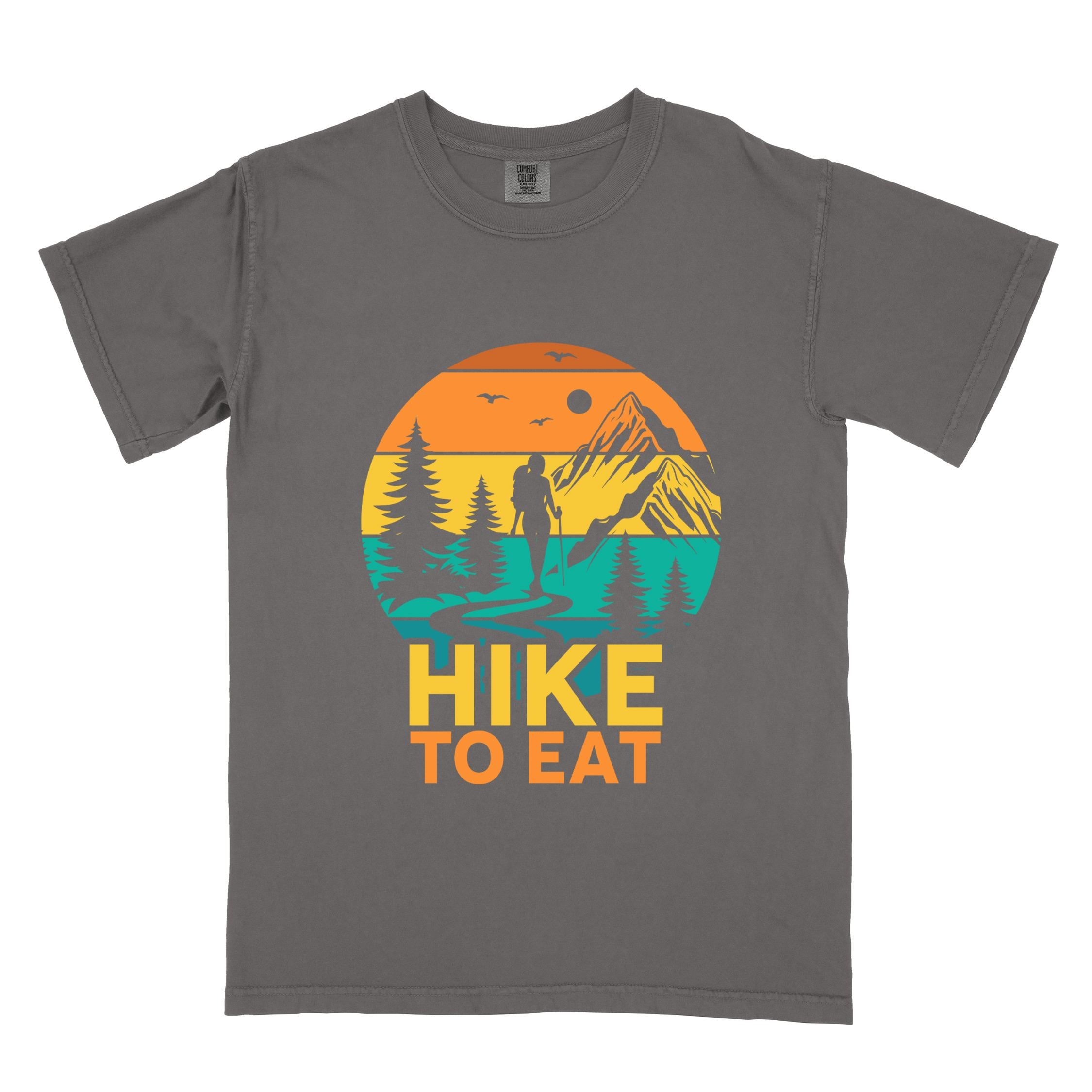 Pepper "Hike to Eat" colored statement tee with bold typography, mountain, sunrise, perfect for adventure driven individuals.