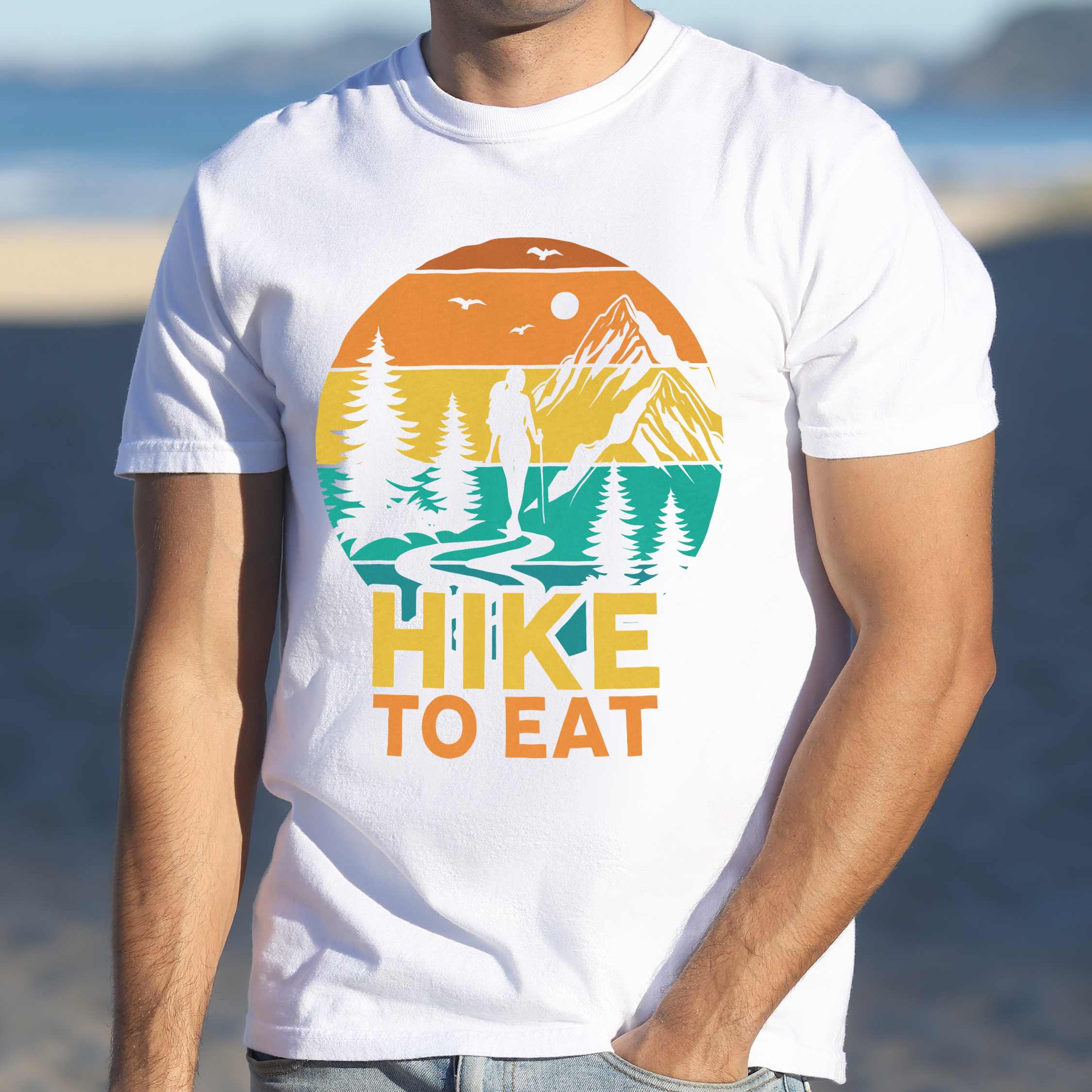 Man wearing white "Hike to Eat" colored statement tee with bold typography, mountain, sunrise, perfect for adventure driven individuals.