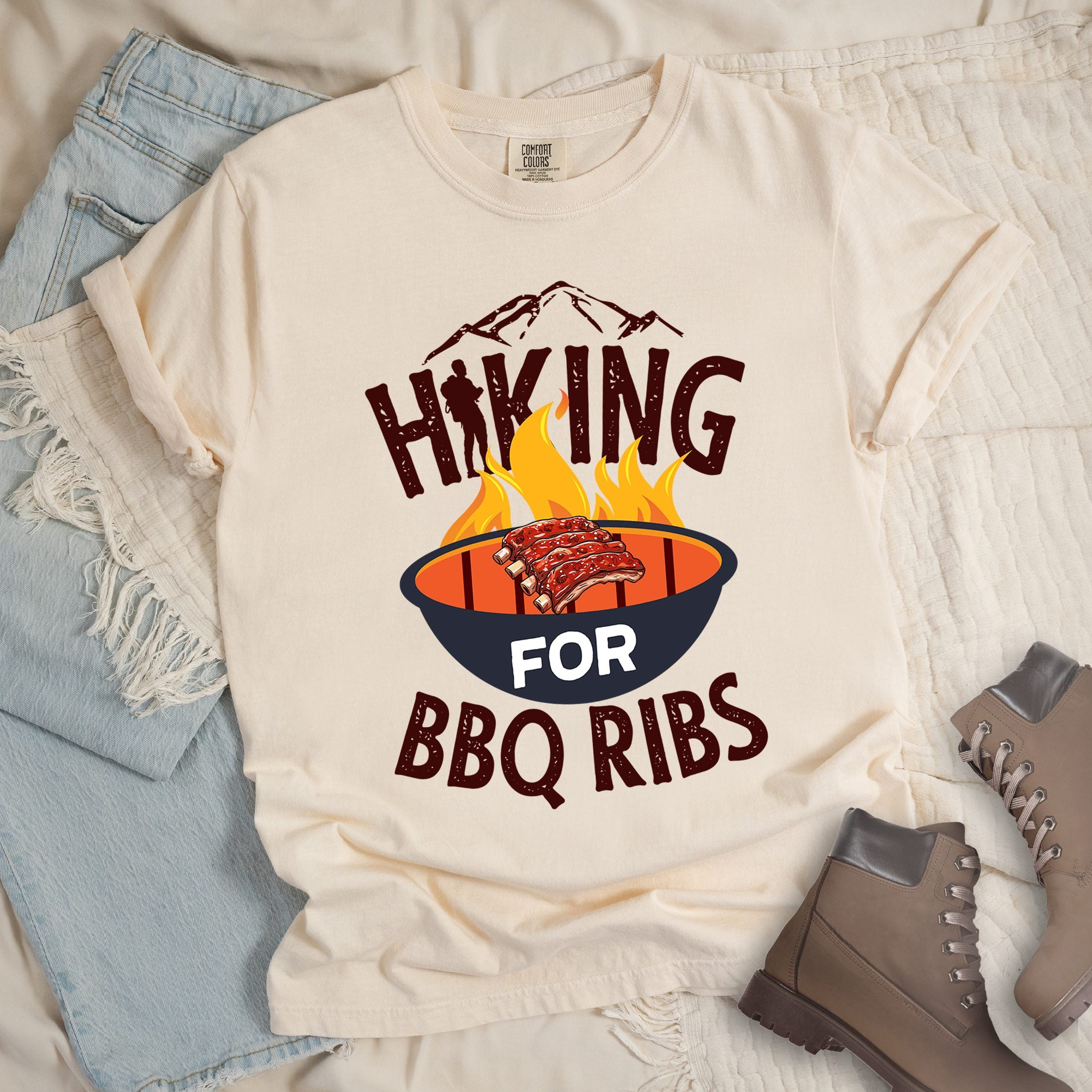 Ivory shirt showing a hiking design with 'HIKING FOR BBQ RIBS' phrase and an illustration of BBQ ribs over a fired up grill