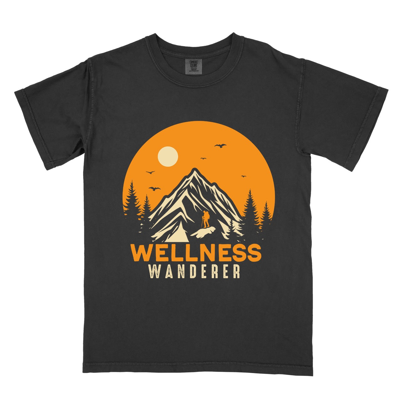 Black Wellness lifestyle vintage tee featuring mountain peak landscape with character silhouette at summit orange sunset circle flying birds pine trees and bold Wellness Wanderer typography on Comfort Colors shirt for nature lovers seeking balance