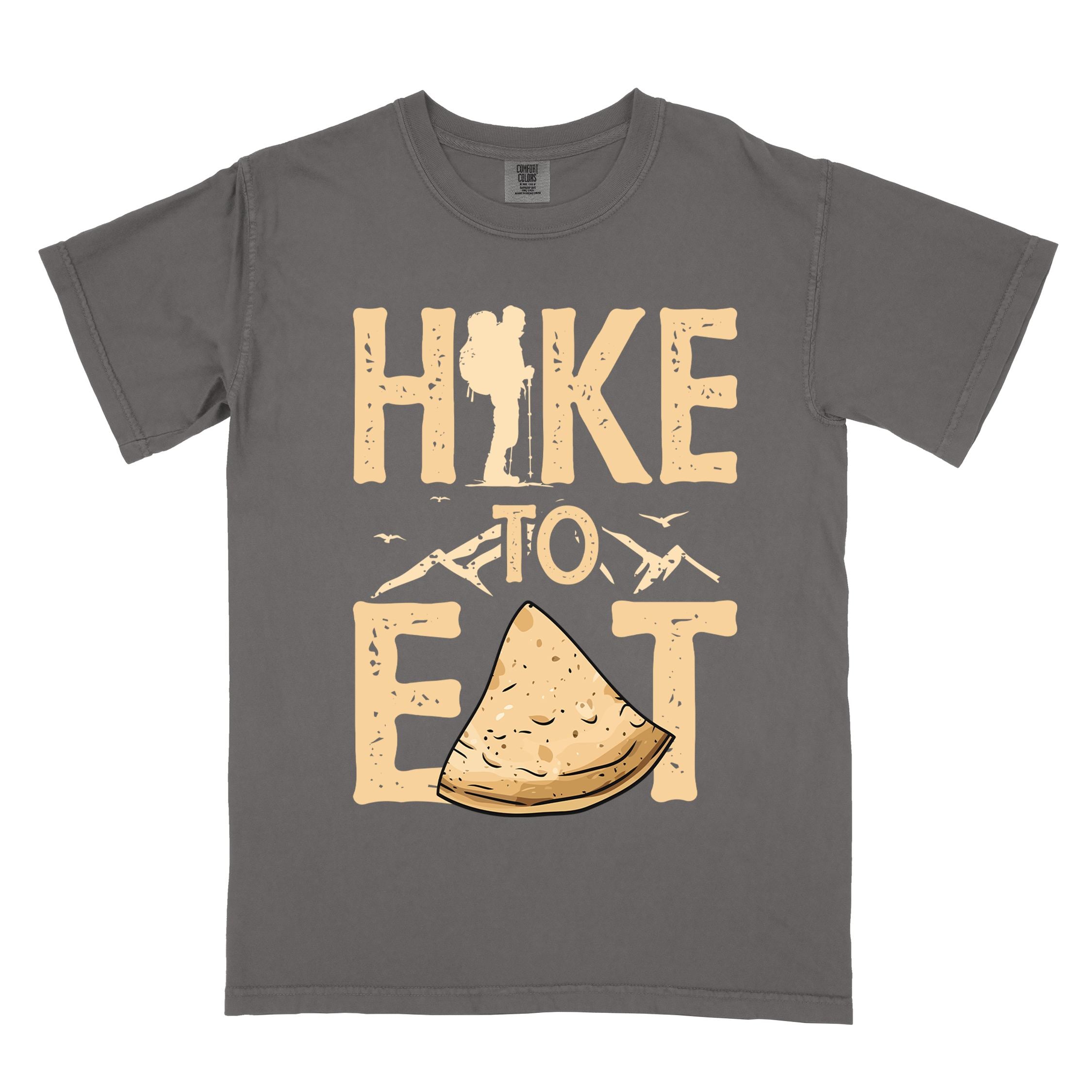 Pepper "Hike to Eat" colored statement tee with bold typography, mountain, illustrated tortilla, perfect for tortilla lovers.
