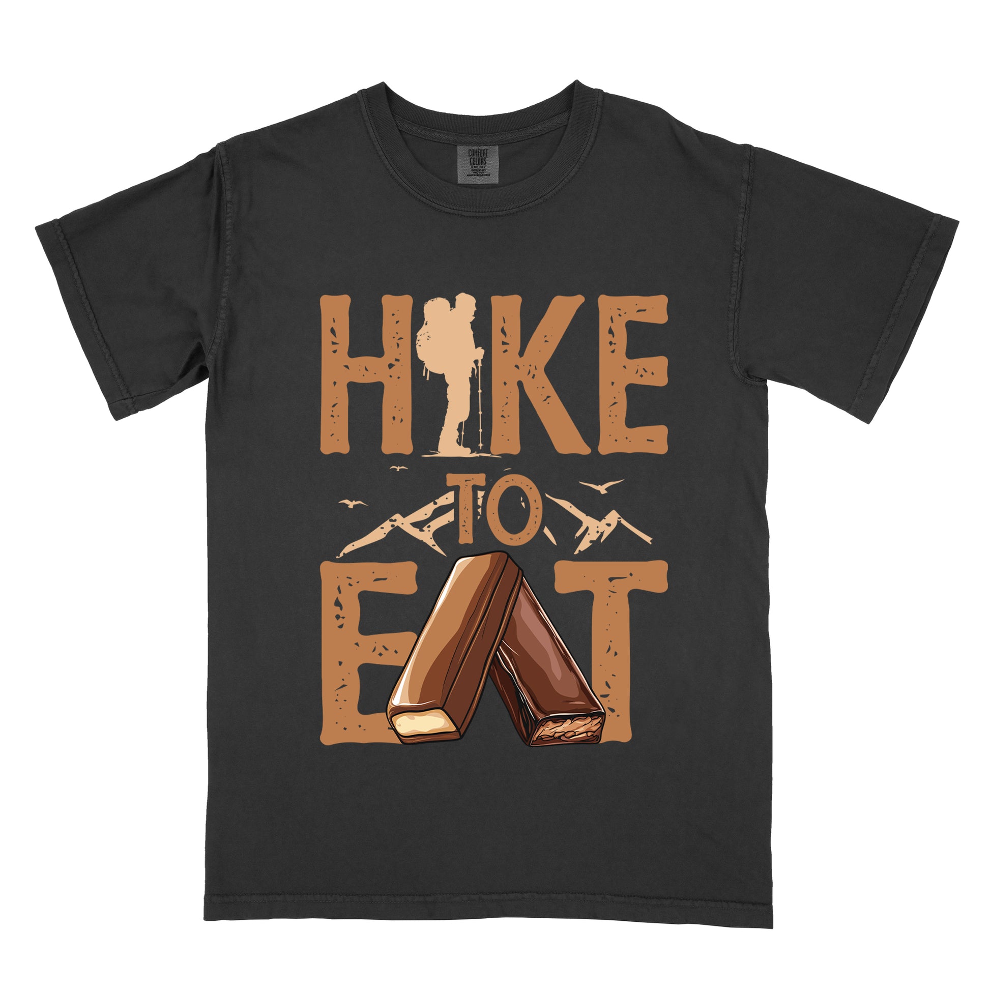Black t-shirt with tan/brown distressed text reading "HIKE TO EAT". "HIKE" appears in large brown letters at the top with a hiker silhouette integrated into the letter "I", "TO" in brown text with small mountain outlines on either side in the middle, and "EAT" in large brown letters at the bottom with two chocolate candy bars arranged in an "A" shape replacing the letter "A". Small flying birds appear near "TO".