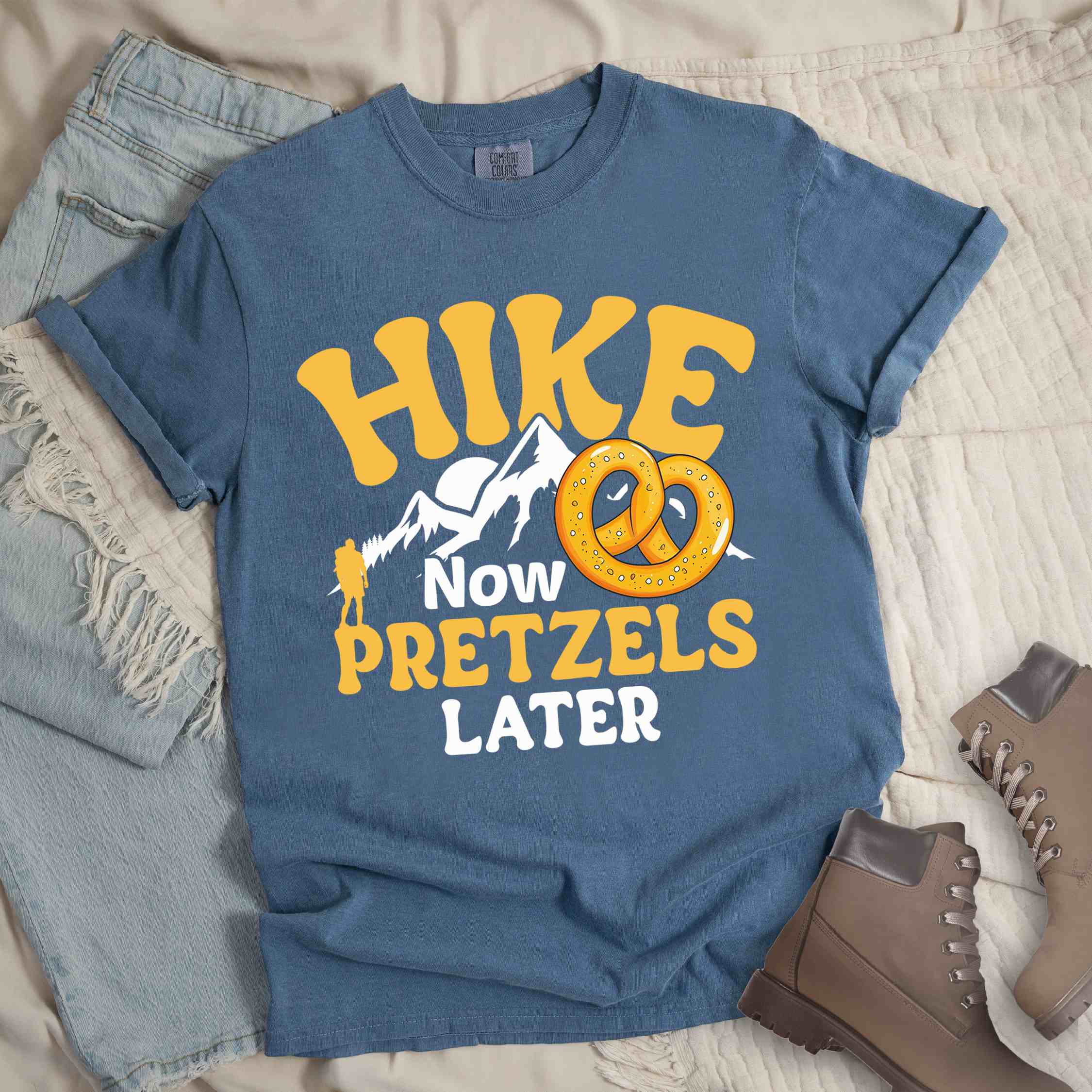 blue jean Hike now Pretzels later colored vintage tee with bold typography, , mountains, sunrise, and illustrated pretzel for baked pretzel lovers