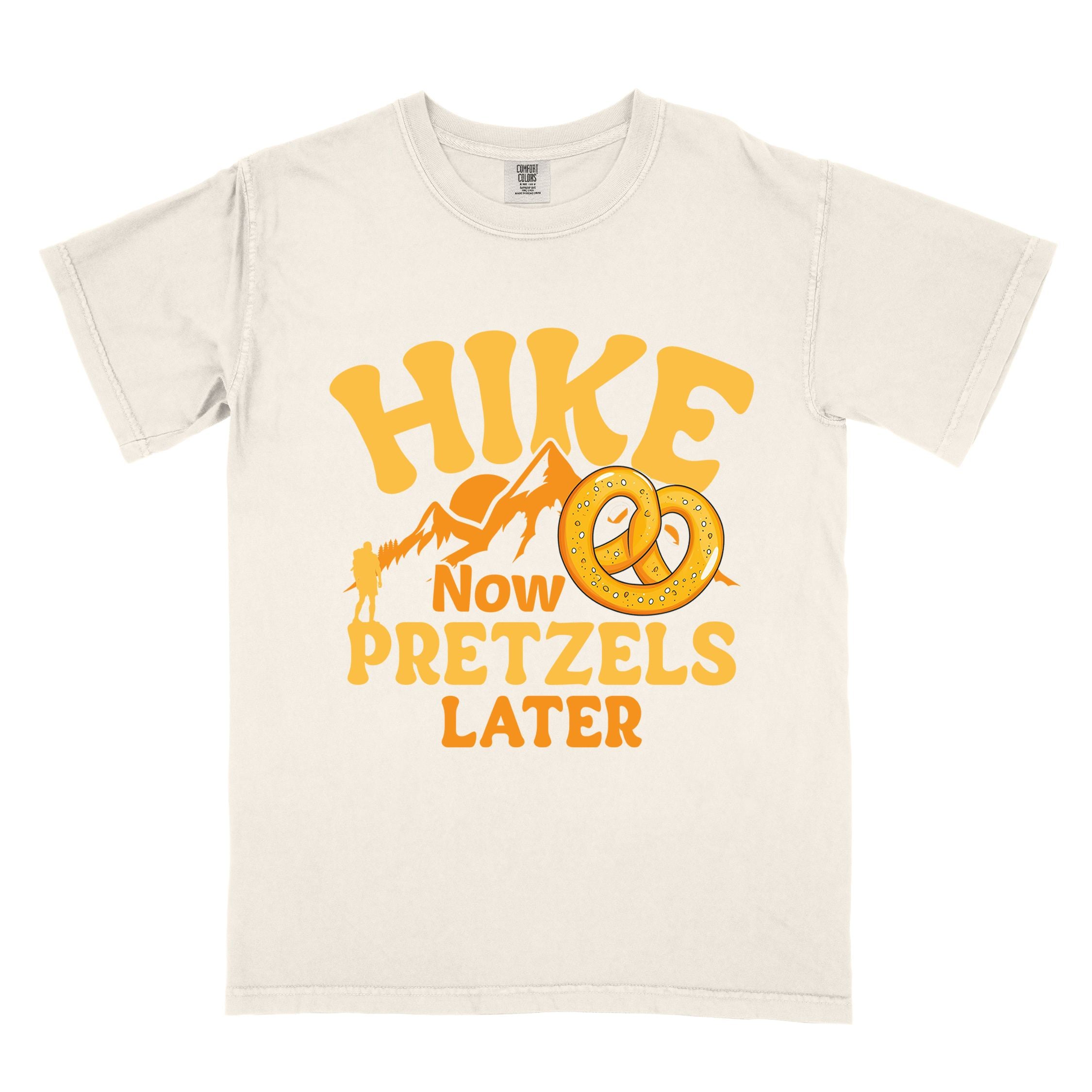 Ivory Hike now Pretzels later colored vintage tee with bold typography, , mountains, sunrise, and illustrated pretzel for baked pretzel lovers