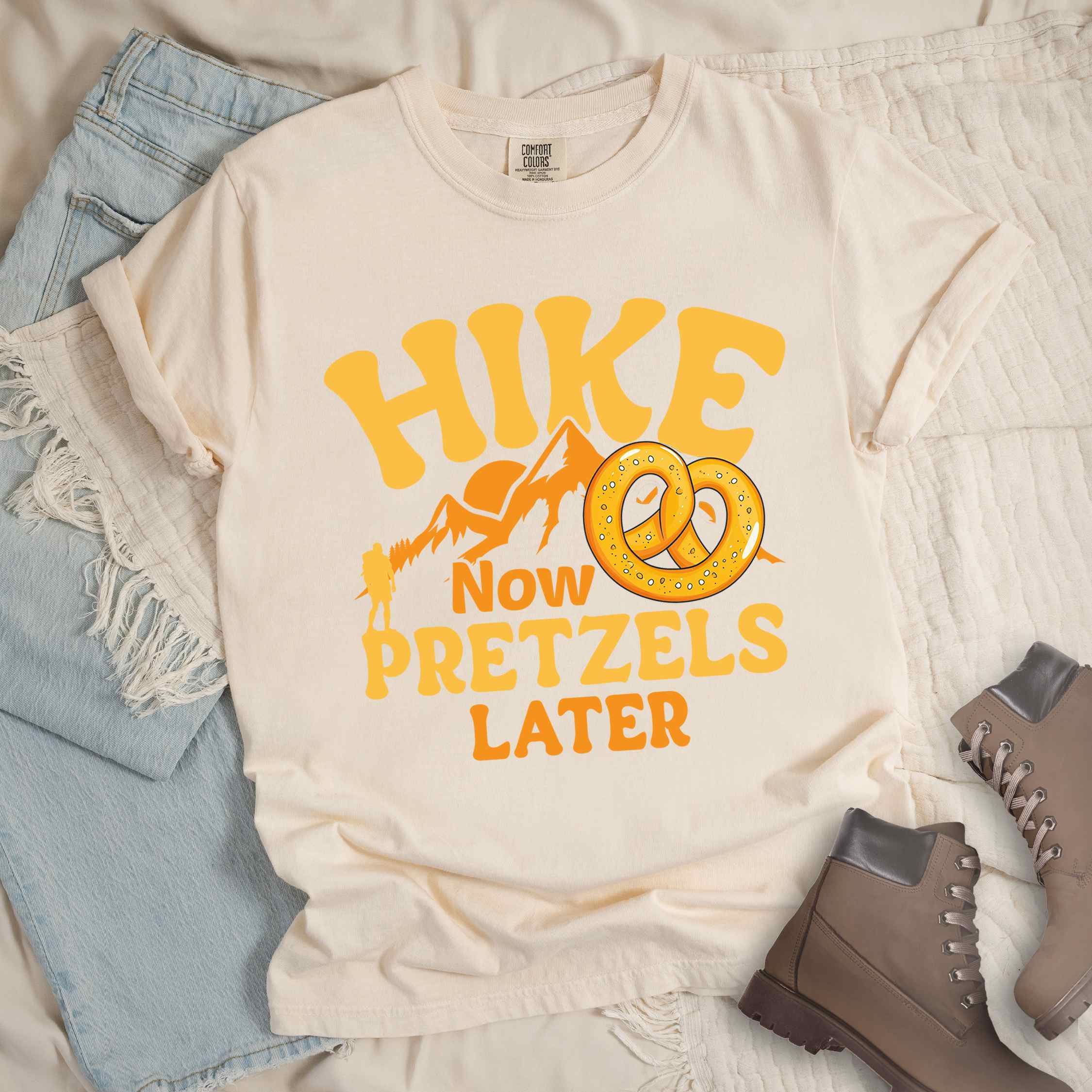 Ivory Hike now Pretzels later colored vintage tee with bold typography, , mountains, sunrise, and illustrated pretzel for baked pretzel lovers