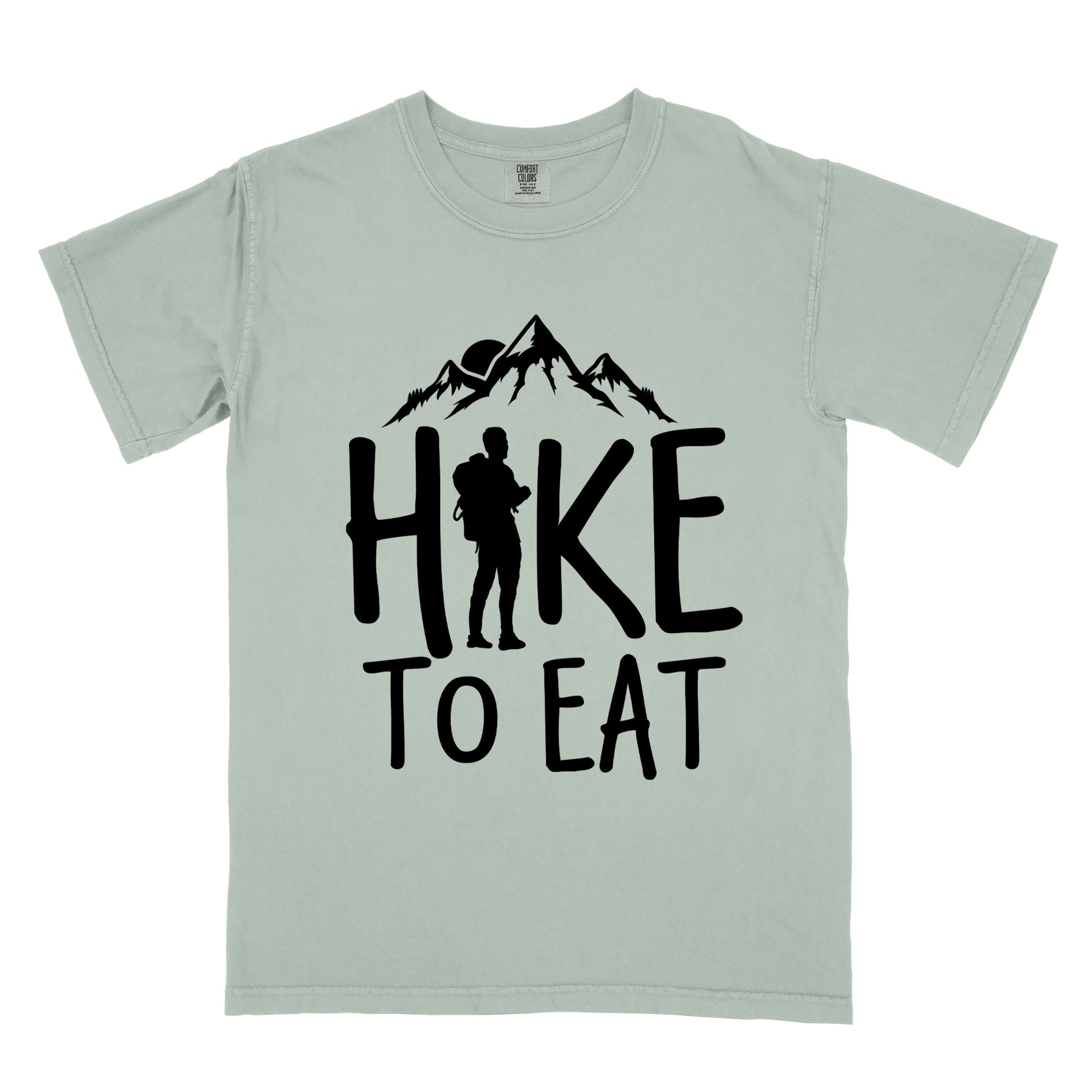 Bay "Hike to Eat" colored statement tee with bold typography, mountains, birds, sunrise, perfect for food motivated individuals.