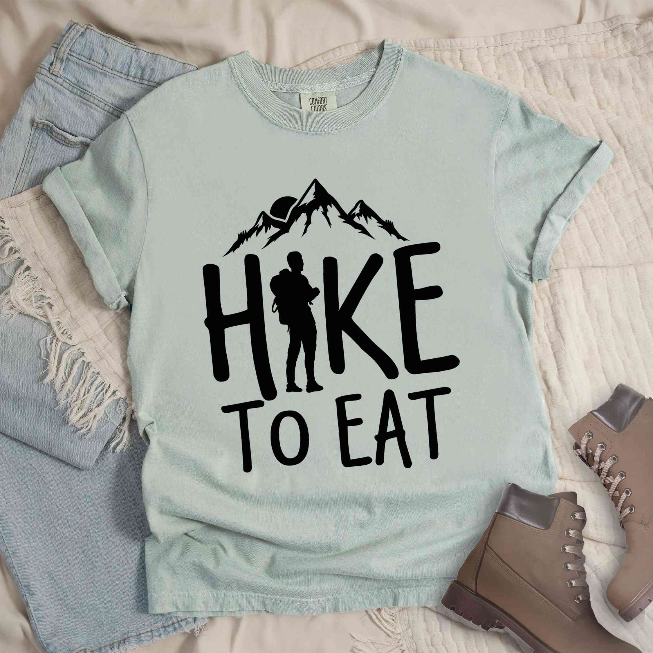 Bay "Hike to Eat" colored statement tee with bold typography, mountains, birds, sunrise, perfect for food motivated individuals.